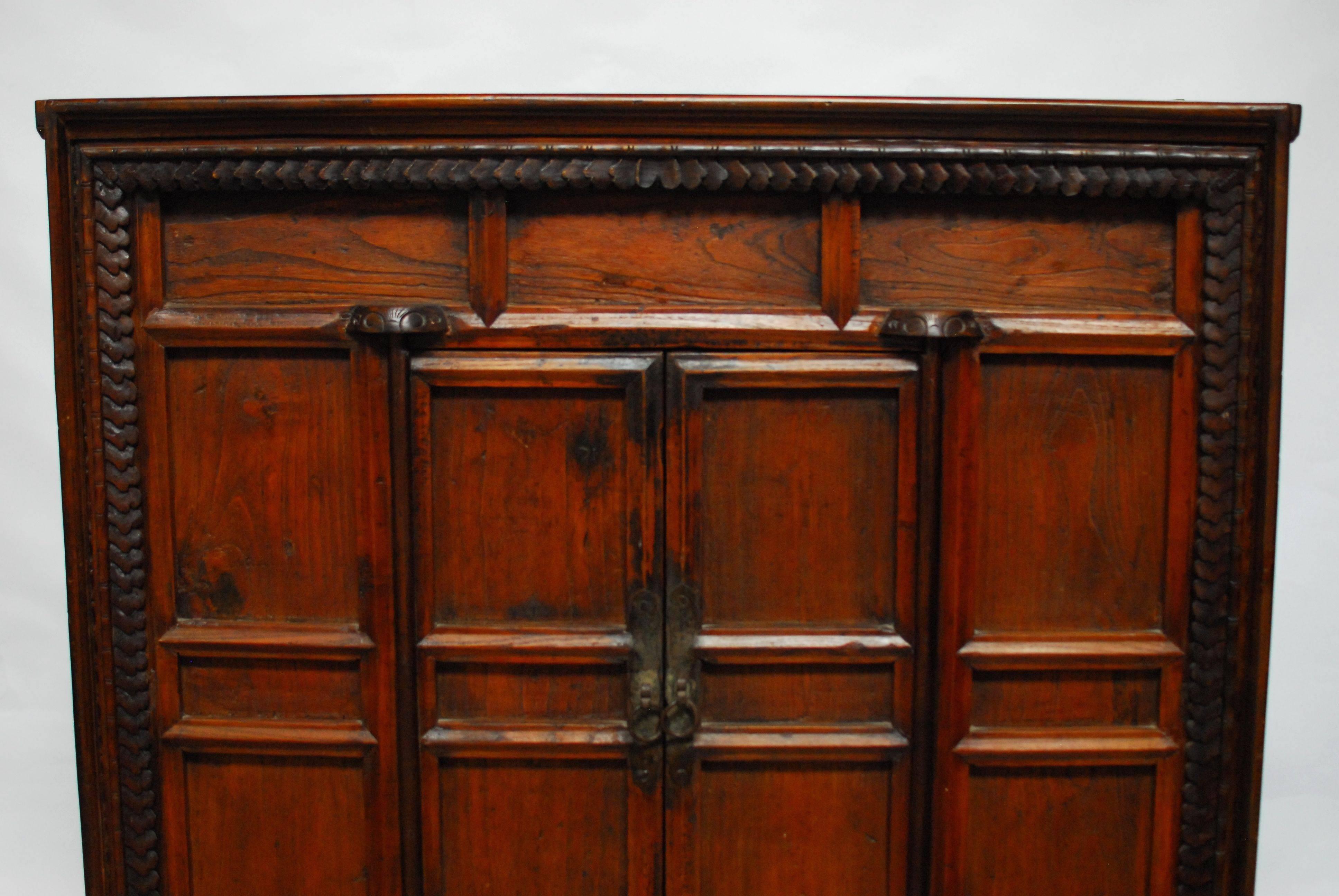 Large, Chinese two-door cabinet chest with a decorative carved front case featuring a Jacobean style border and a faux bamboo trim next to it. Two small doors open to a large open two shelf storage area. Mortise and tenon joinery throughout and