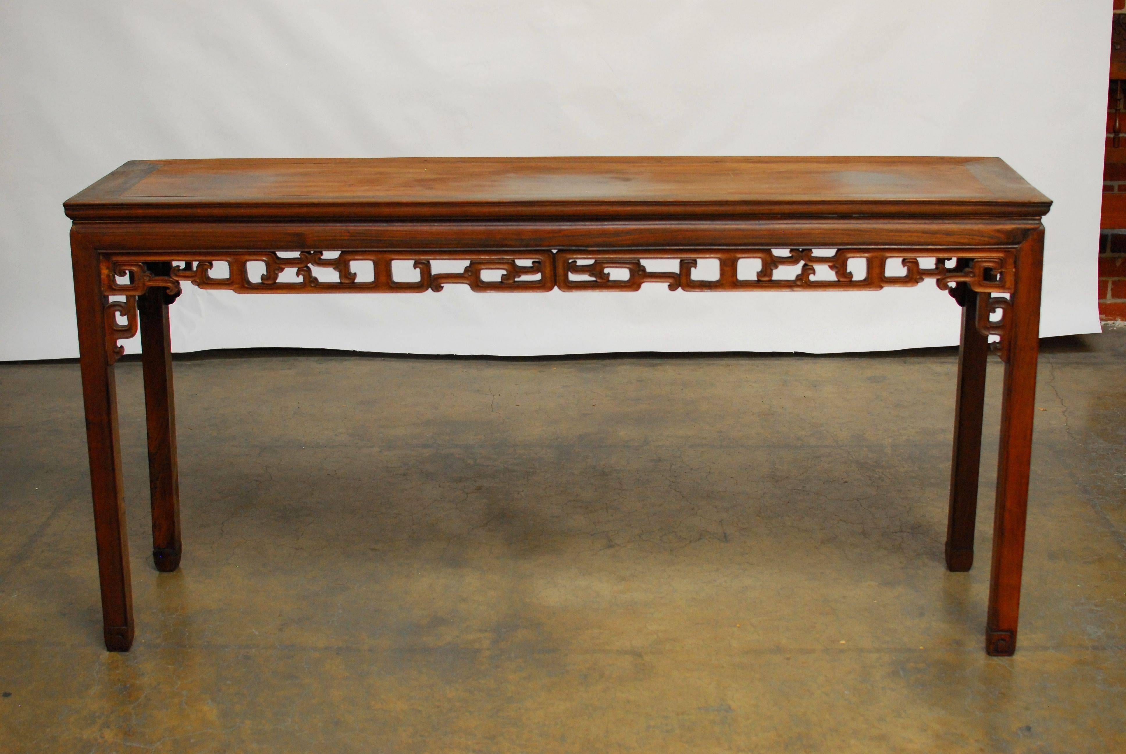 19th century Chinese rosewood altar table with pierced and carved frieze on square legs and scroll feet. Also known as a scroll table, or long console for viewing scrolls. From Qing dynasty era. From a collector’s estate in San Francisco CA.