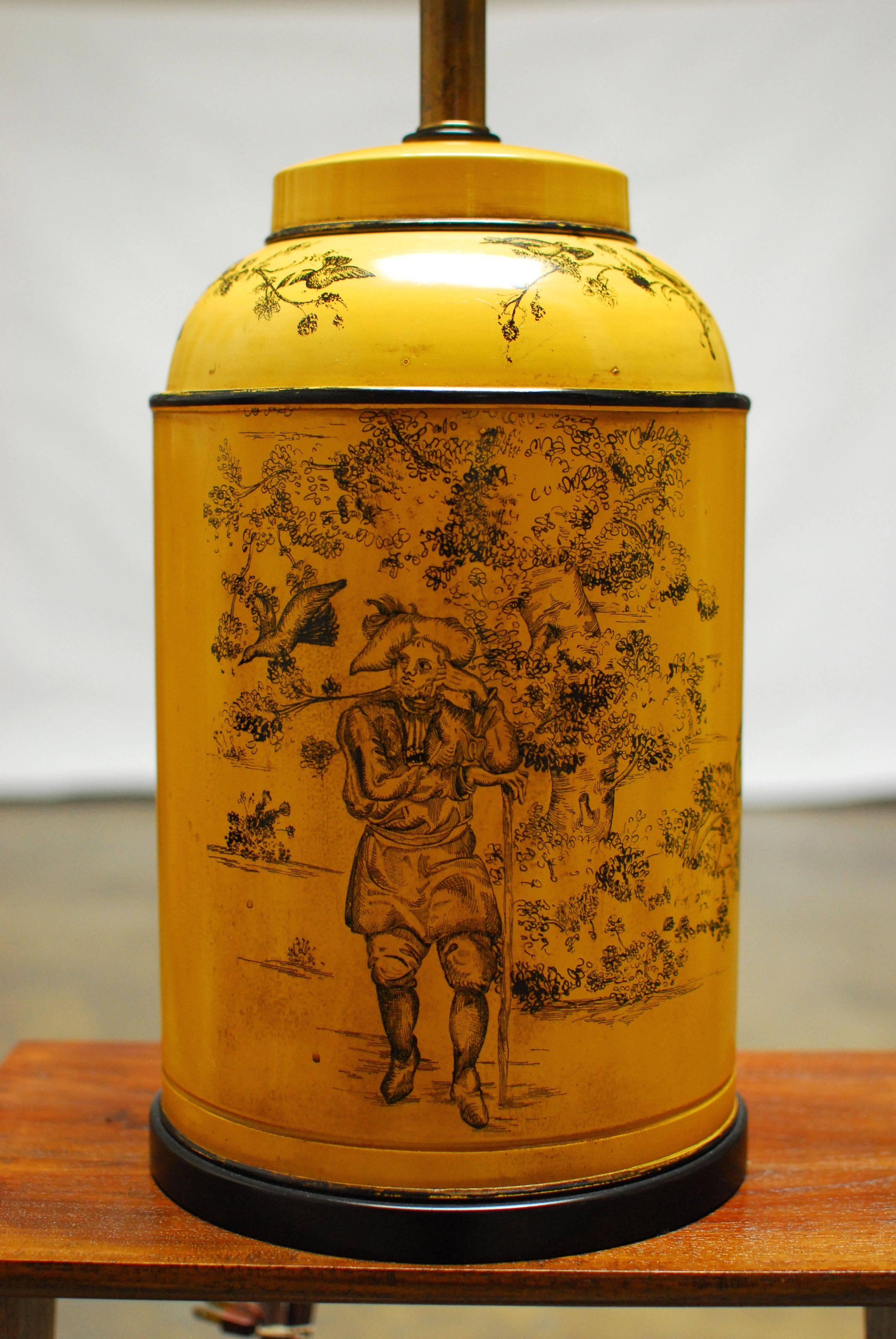 French Provincial style tea canister tole lamp finished in mustard yellow with French country scenes. Made by Frederick Cooper of Chicago with brass metal hardware. Sits on a round conforming wood base and includes a matte black finial and