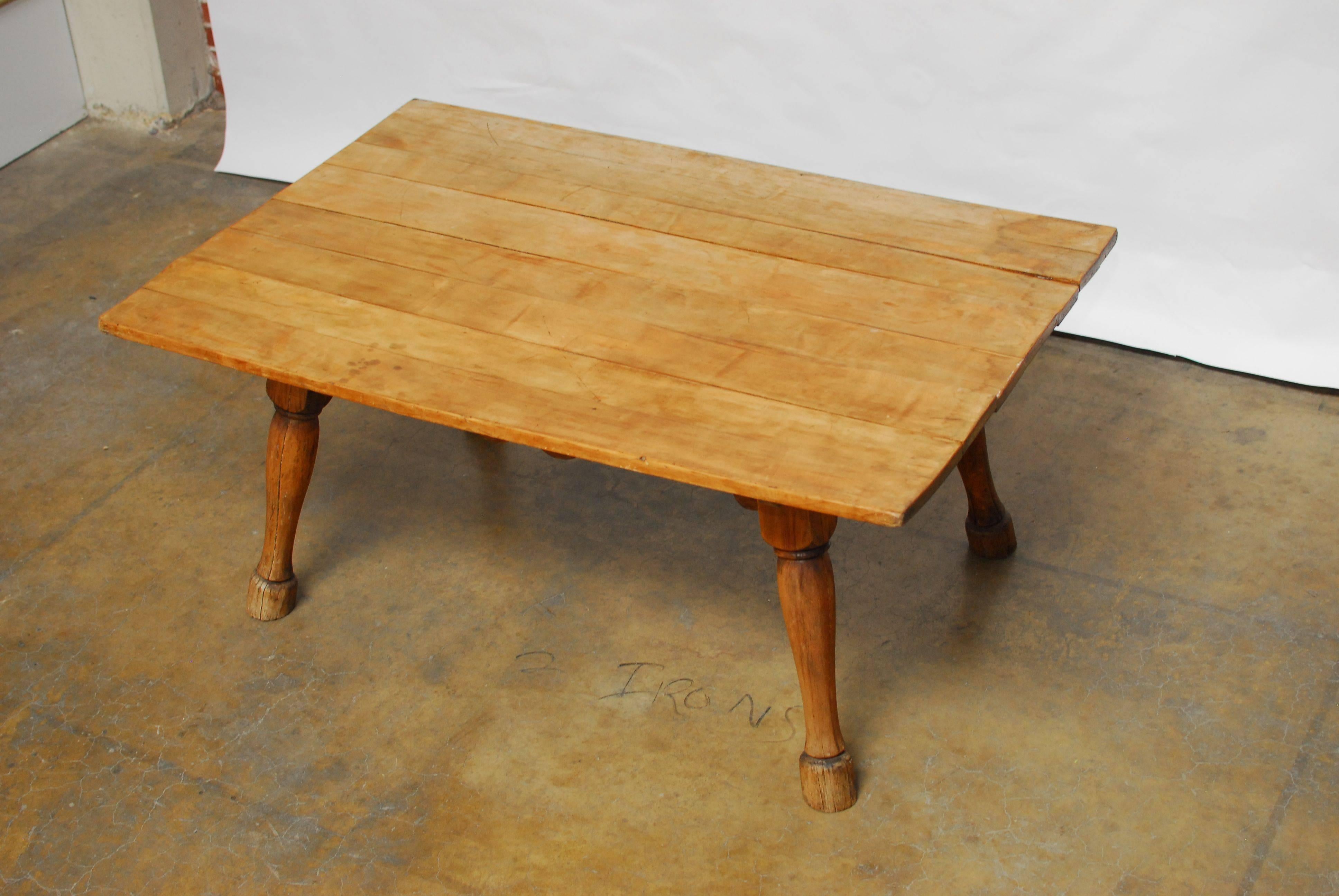 A Primitive, English tavern table with a rectangular top and featuring strong splayed horse hoof form legs. The plank top is made of eight slabs over one inch thick. The top is removable and has decorative carved apron. The wood has a rich, soft