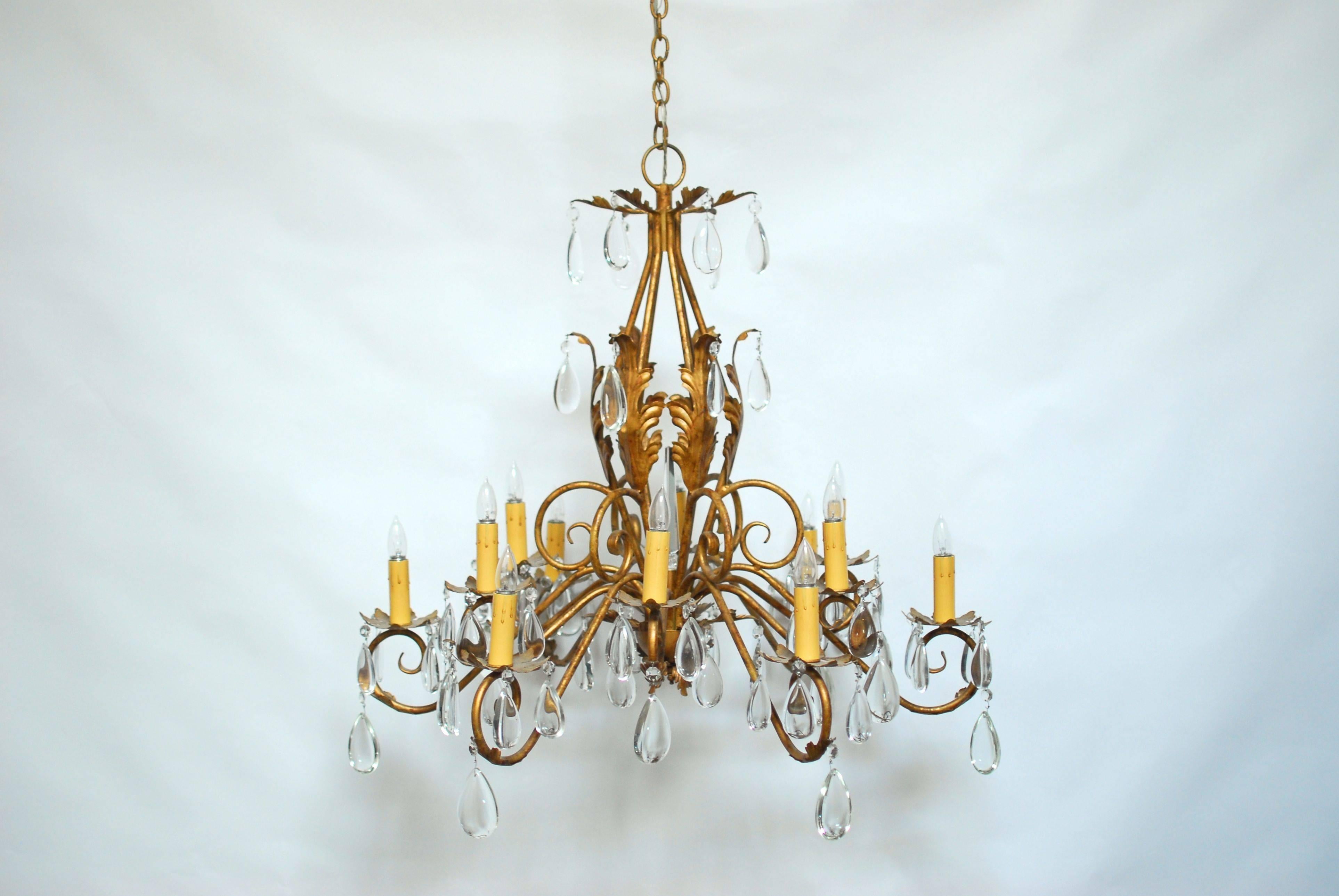Elegant Louis XV style twelve-light gilt metal chandelier with scrolled arms and foliate bobeches topped by wax candle lights. Decorated with 78 huge, cut crystal teardrops hanging from Acanthus leaves. Centered by a long, tapered cut crystal.
