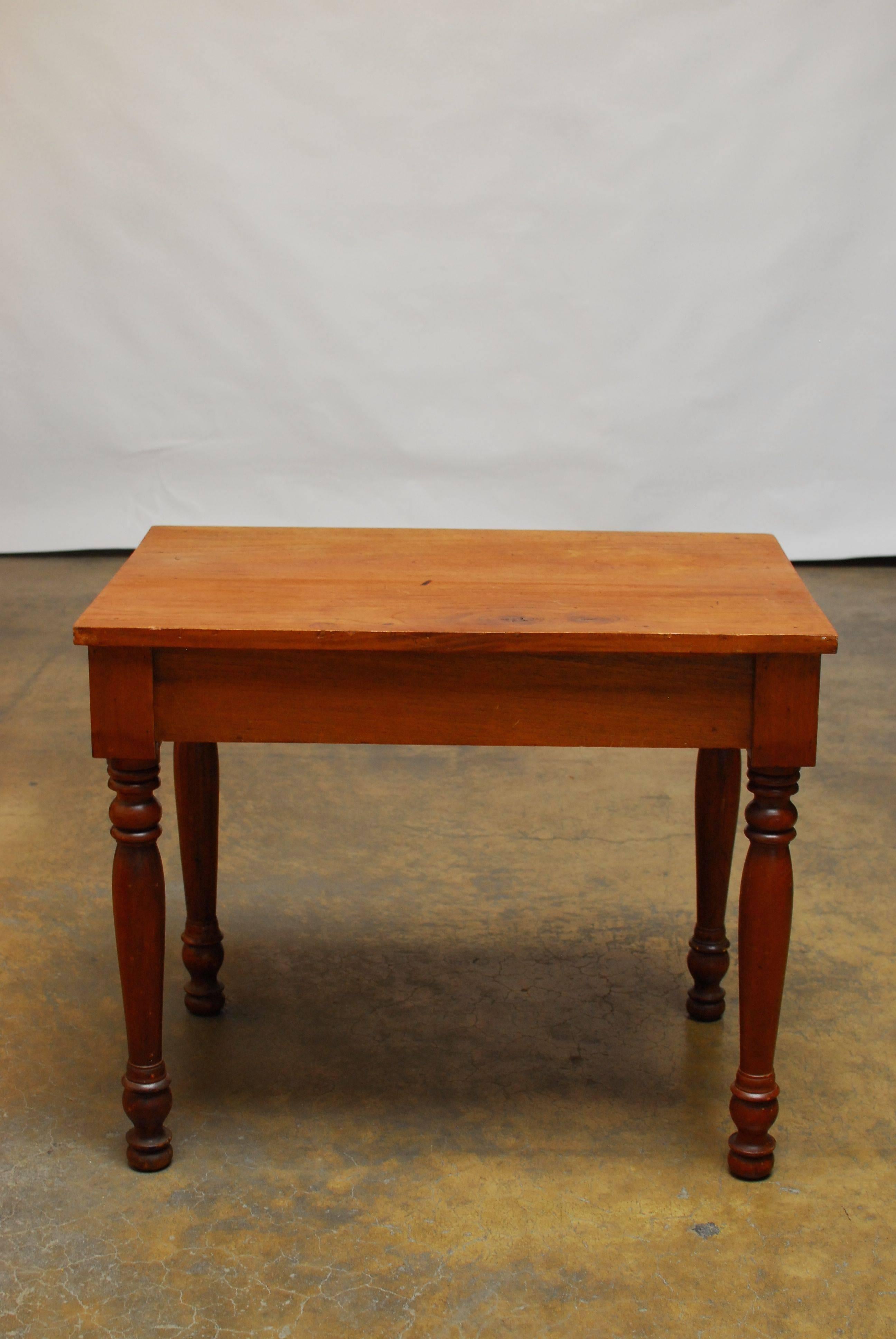 Primitive American farm table desk or work table made of walnut and fronted by one large drawer with wooden pulls and dividers inside. Thick top slab of wood with a rich worn patina. Sits on long, turned legs and is very sturdy. The case is
