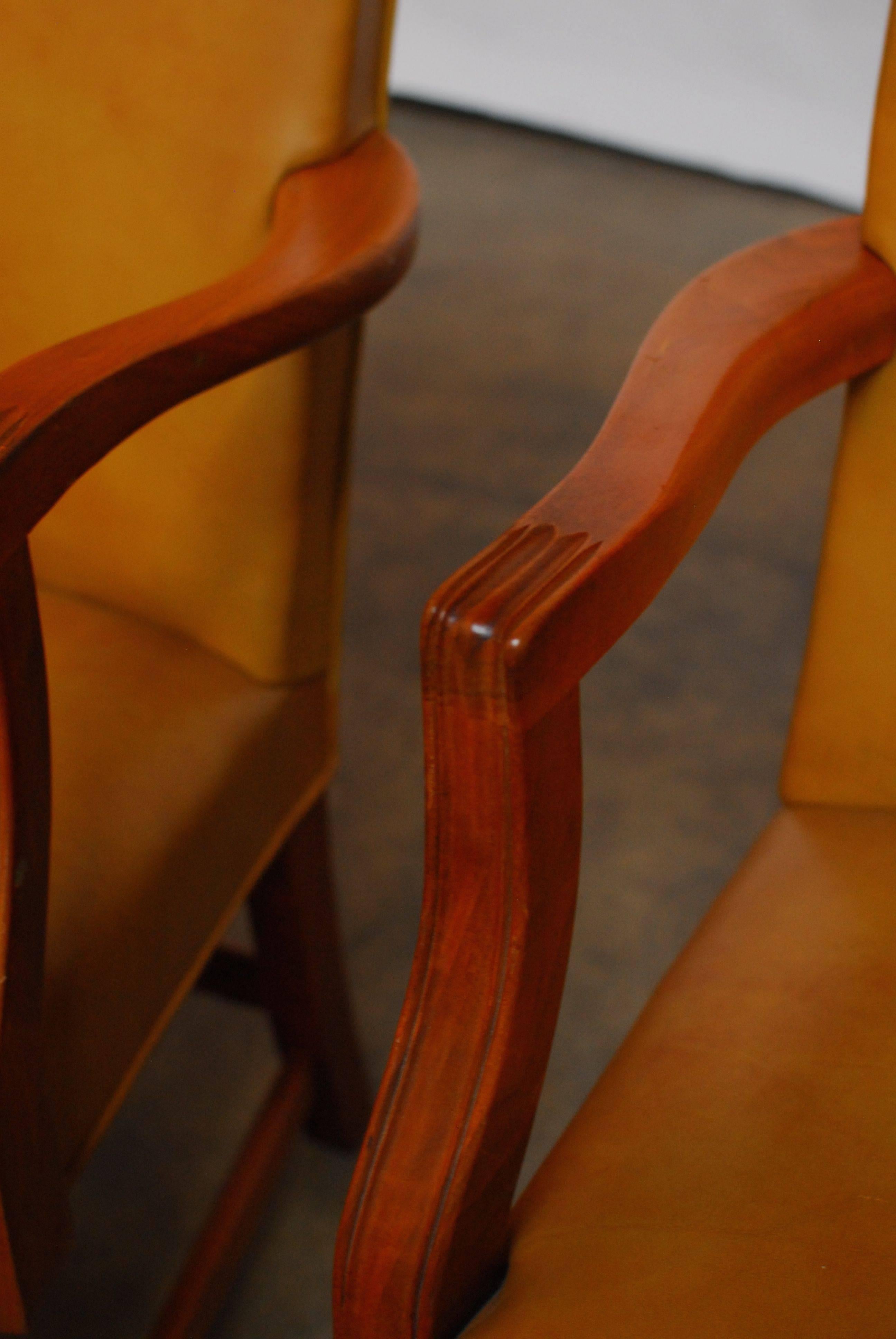 Pair of handsome Chippendale style library chairs made by Johnson Chair Co. of Chicago. Featuring rich leather upholstery accented by brass nailheads and a high back with a serpentine crest. The shaped arm supports are molded and the rear legs flare