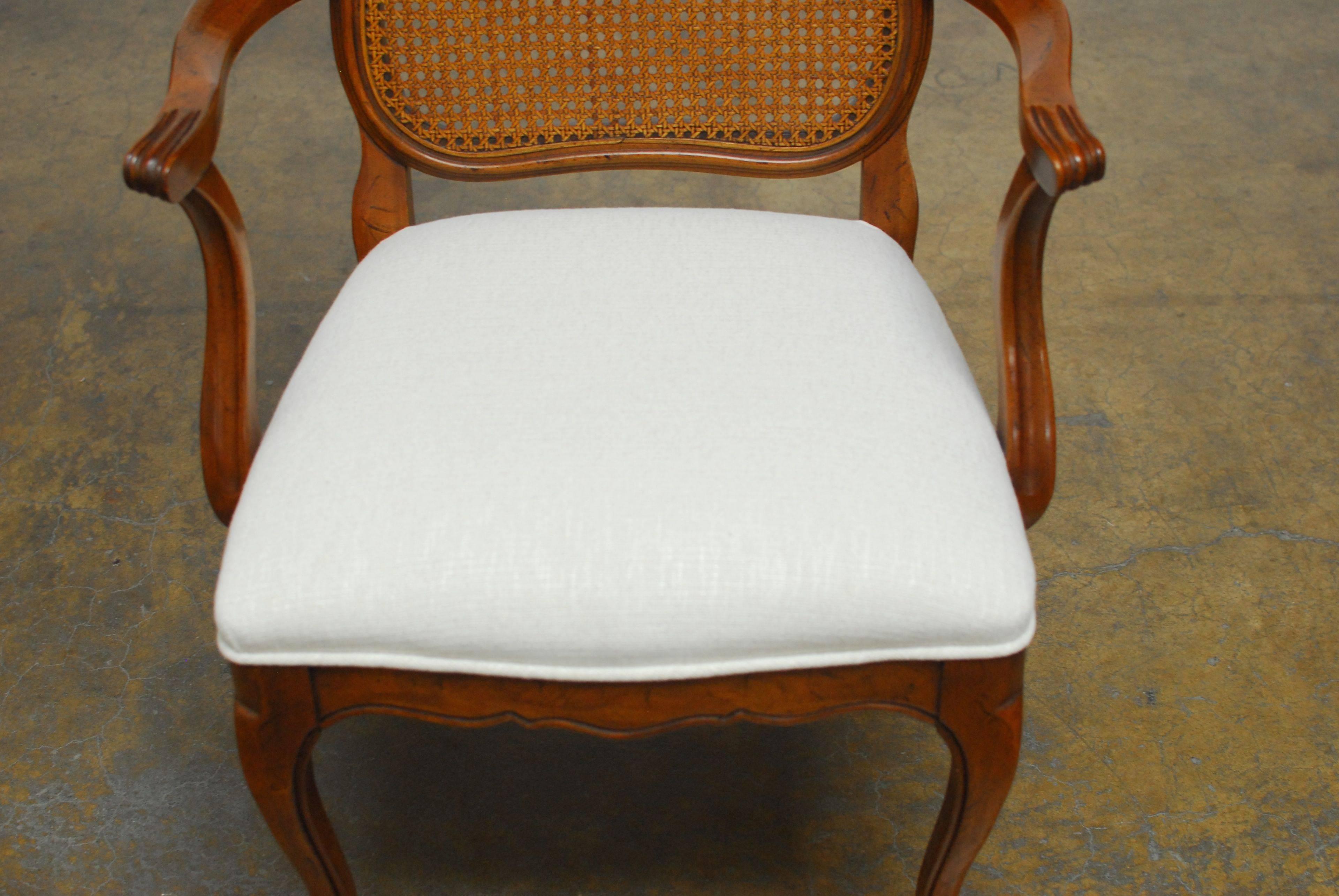 Exquisite set of eight dining chairs consisting of six side chairs and two armchairs featuring a caned back. Made in the Louis XV style with cabriole legs and a scalloped apron. Freshly reupholstered in a white chenille and exceedingly well made