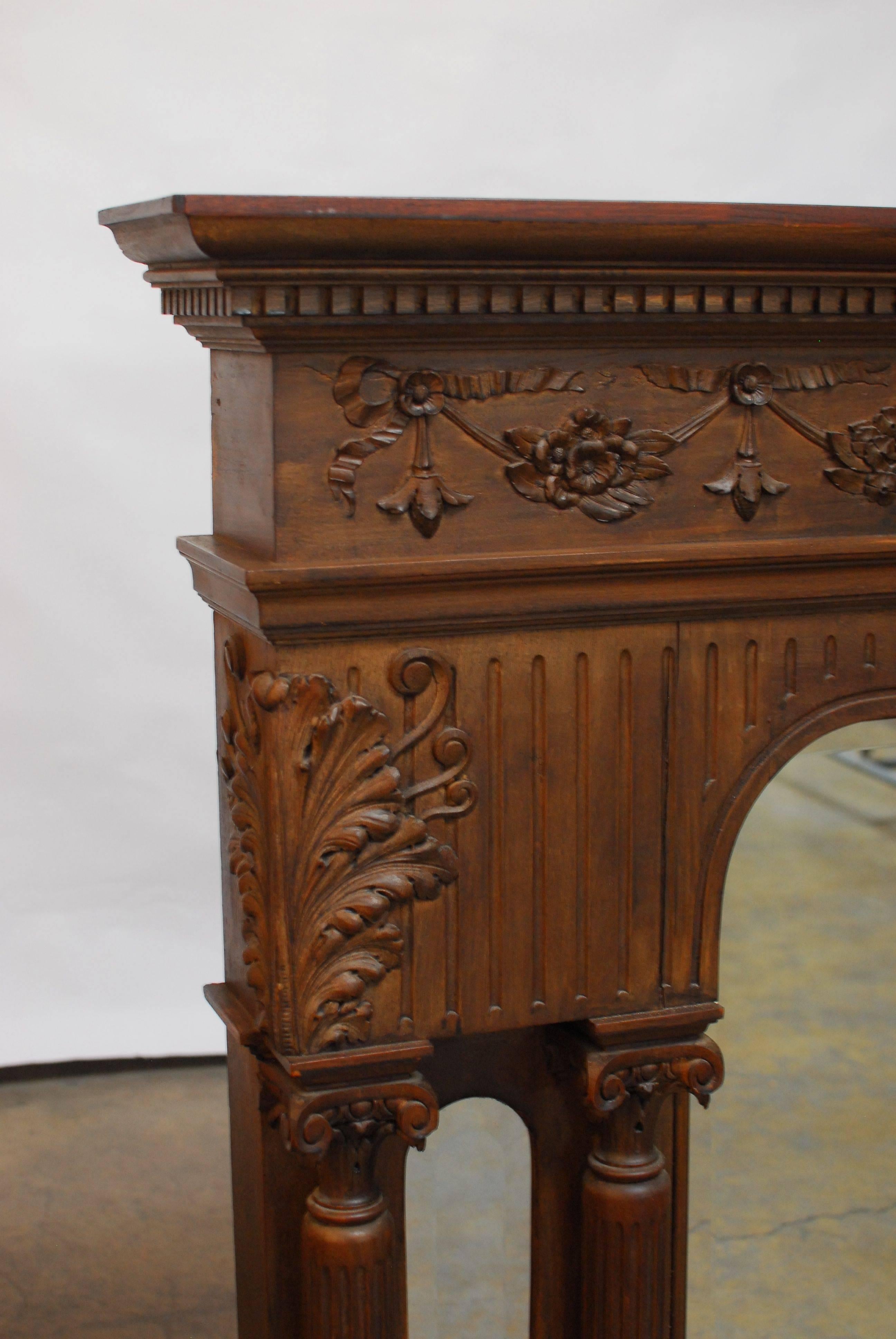Highly carved Victorian over mantle mirror featuring four Neoclassical style corinthian columns. Two arched mirrors flanked by one larger arched center mirror all having beveled glass. The mirrors are surmounted by a large cornice shelf with