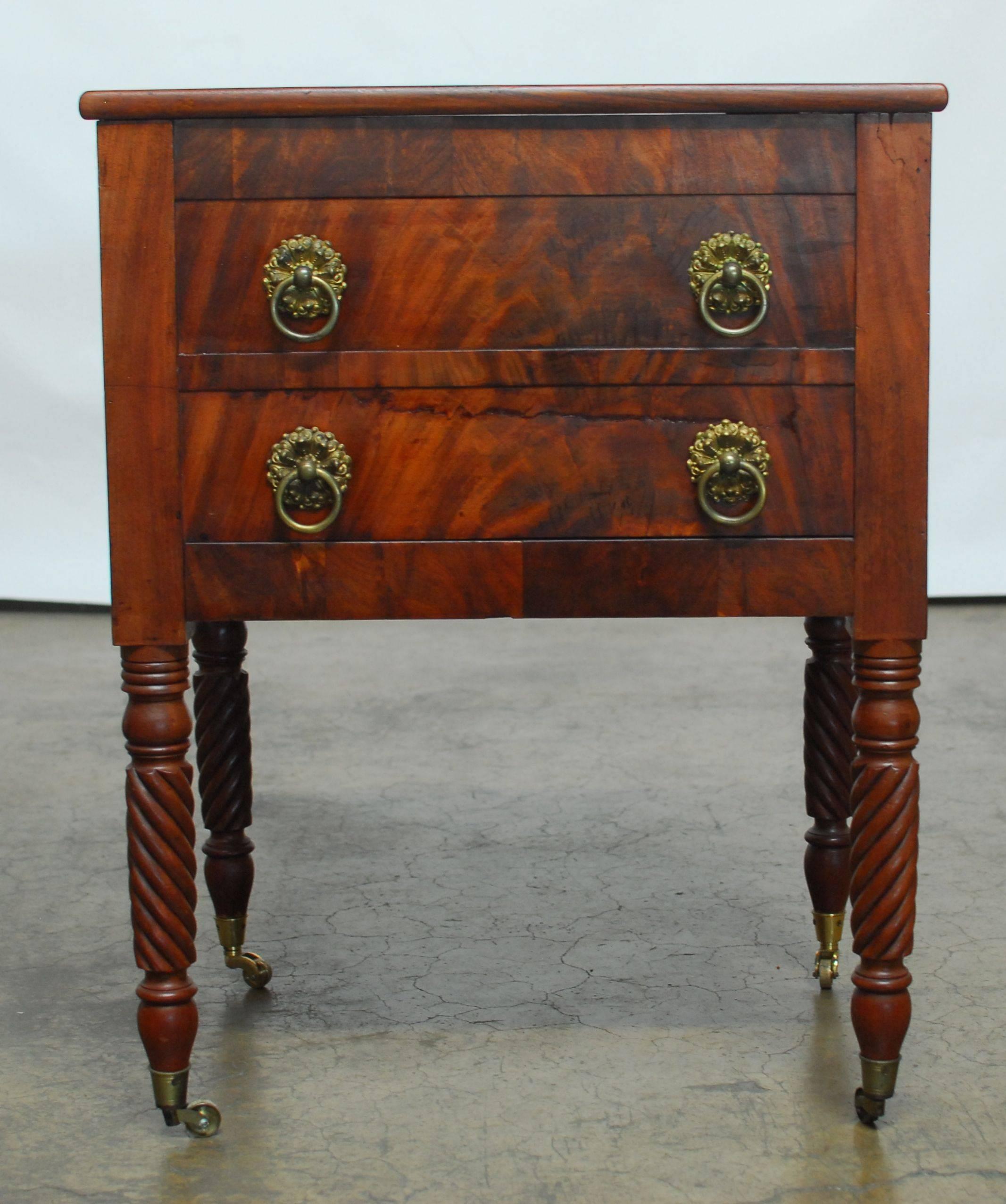 Federal period work table made of mahogany featuring barley twist legs. The case is fronted by two false dummy drawers and a hidden drawer on the bottom decorated with brass pull rings and round escutcheon. The top is hinged and opens to a large