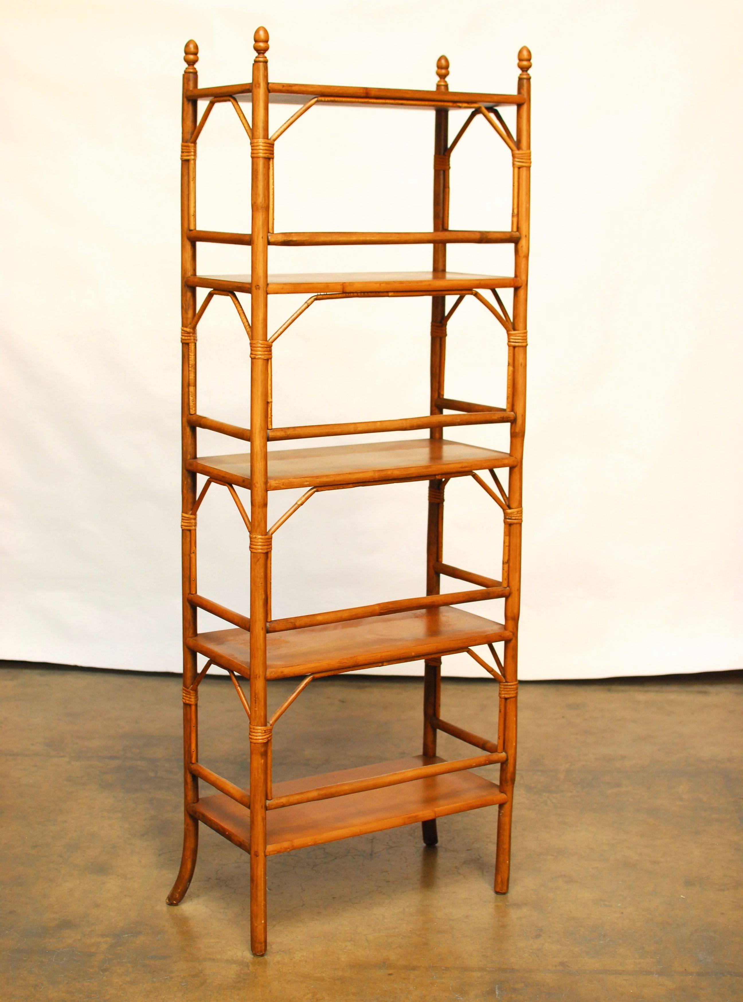 A pair of vintage Hollywood Regency faux bamboo etageres made of carved wood with wood peg joinery and accented with rattan decorative fretwork spandrels and finals. The front legs are splayed on the ends and these etageres feature five display