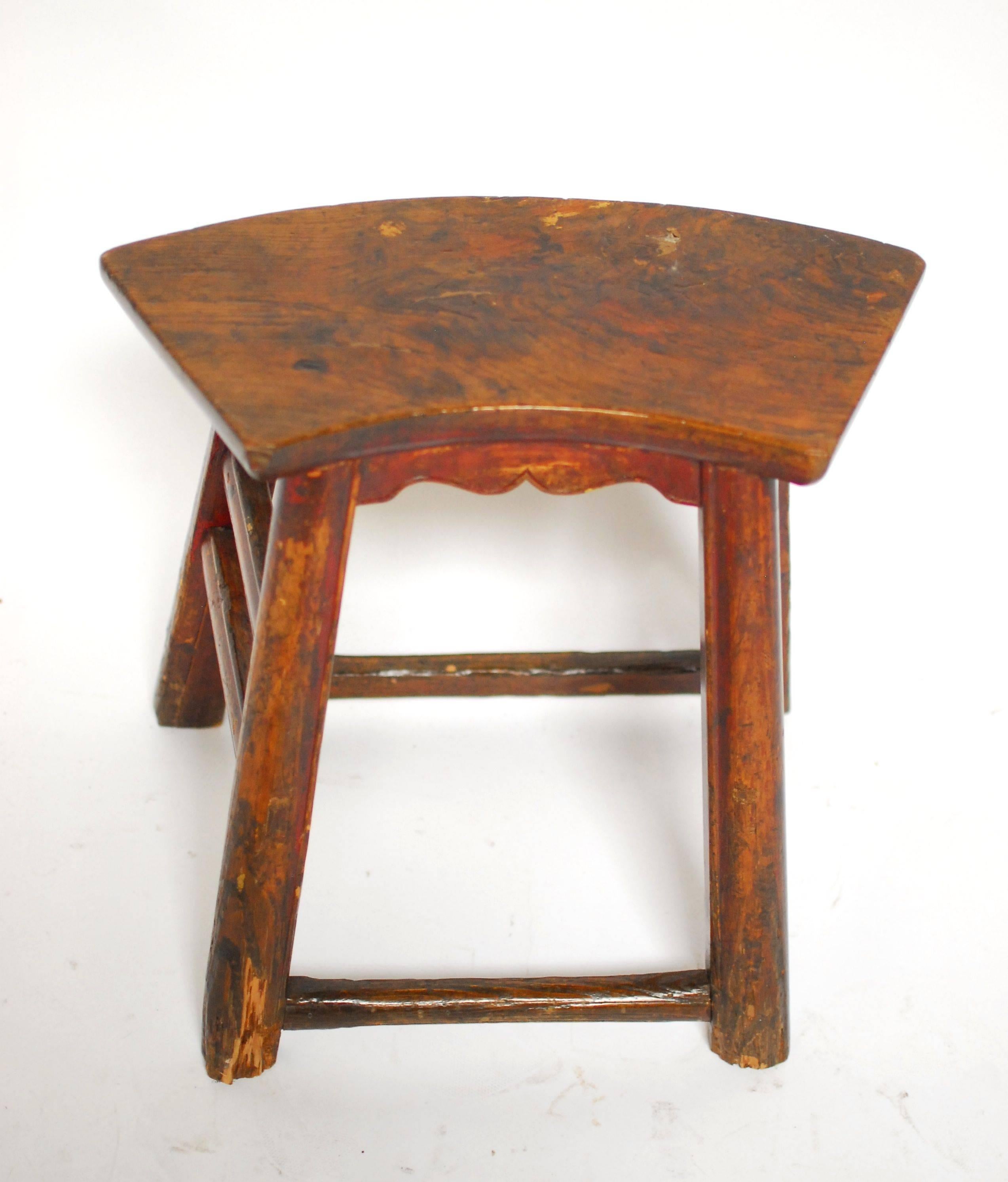 Chinese carved wooden stool with a fan shaped seat. Features splayed legs with stretchers on each side and a carved apron on the front. Constructed with old world mortise and tenon joinery and bead edge detail on the legs and side stretchers.

