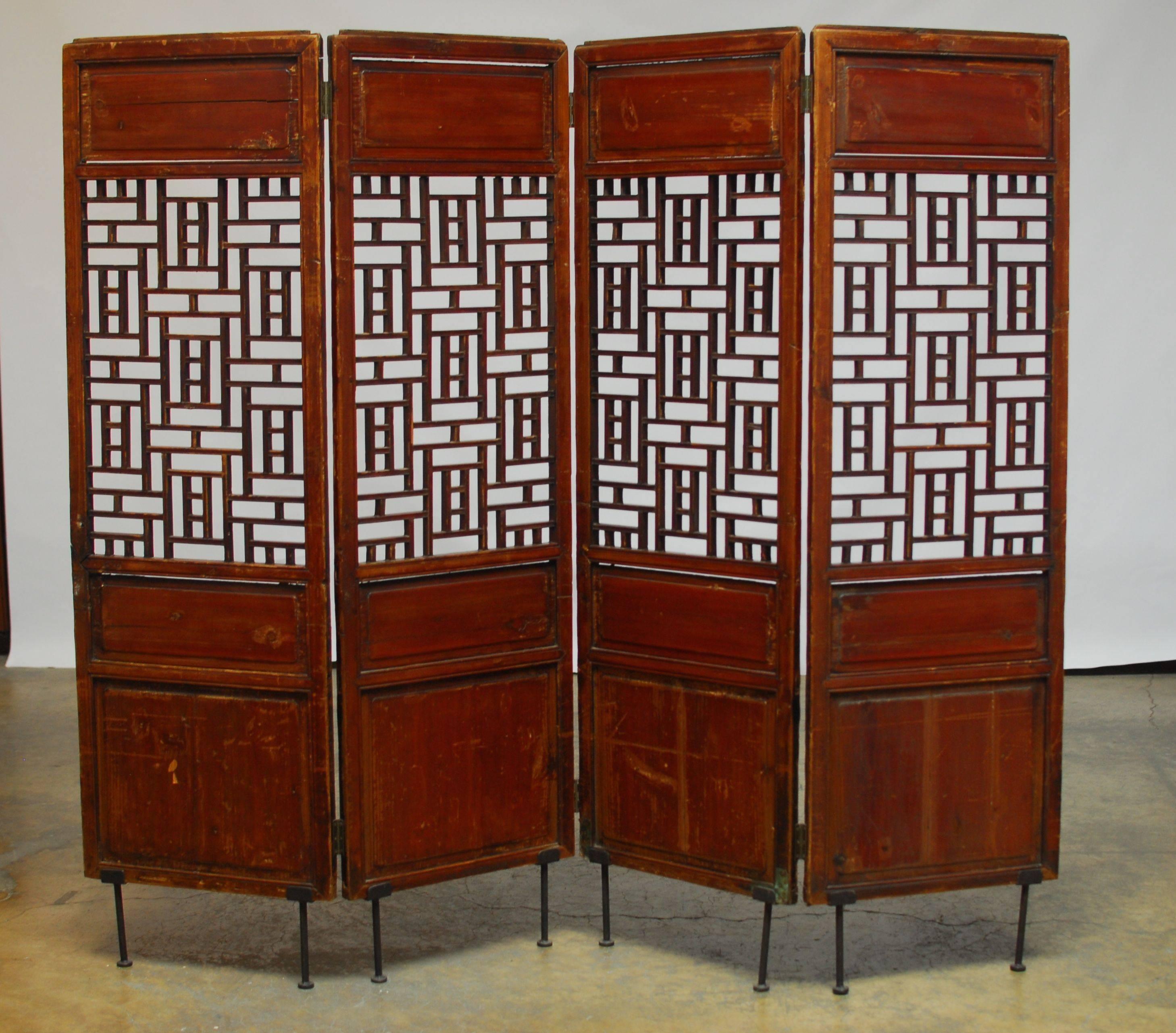 19th century Chinese screen featuring a geometric lattice window in each panel. Constructed with old world mortise and tenon joinery and mounted on iron feet. Originally four separate carved elm panels now joined and lifted for display.
   