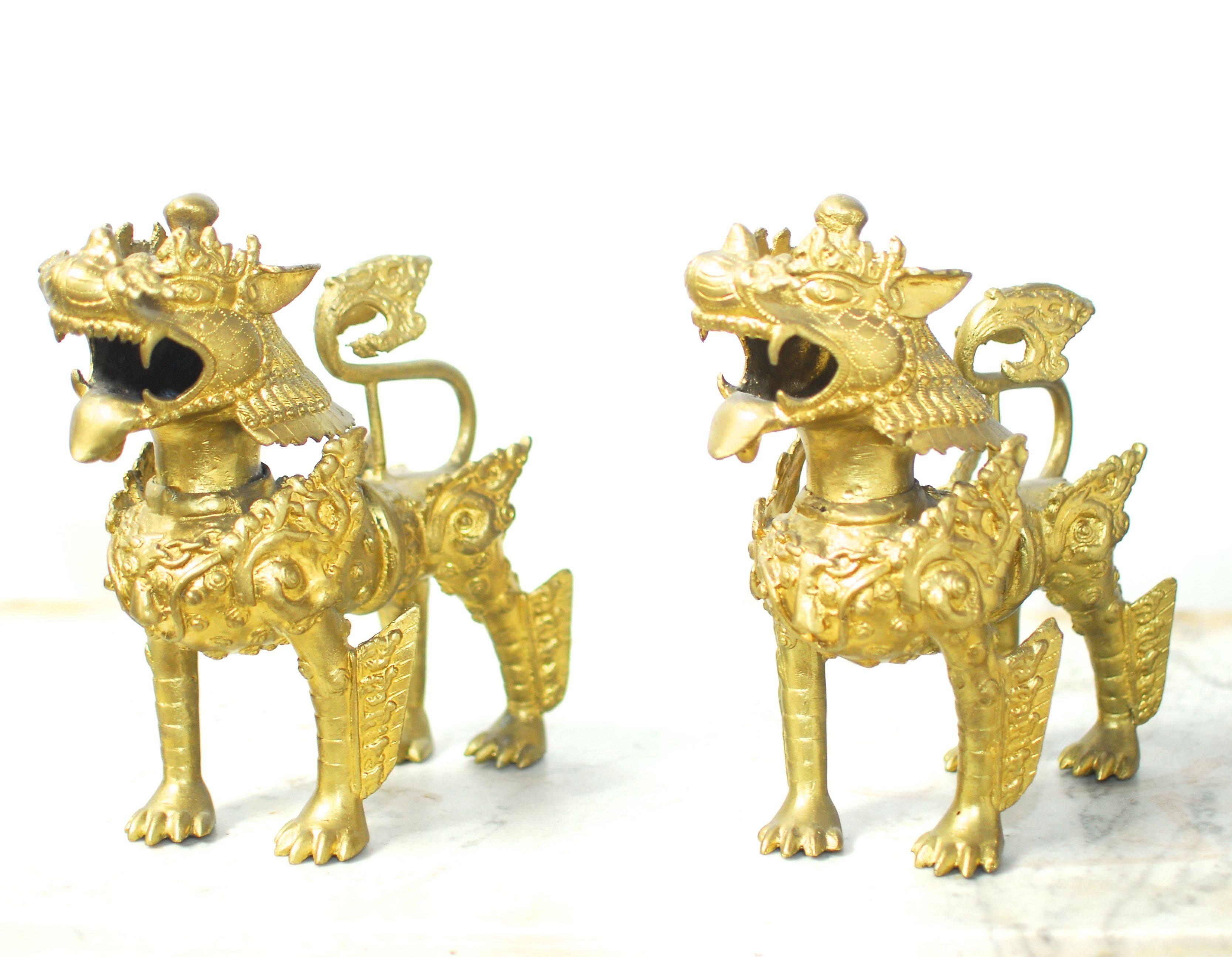 Chic pair of Southeast Asian gilt foo dogs made of solid brass. Intricate details with fierce expressions. Also known as temple dogs. Each one weighs 10 pounds.
