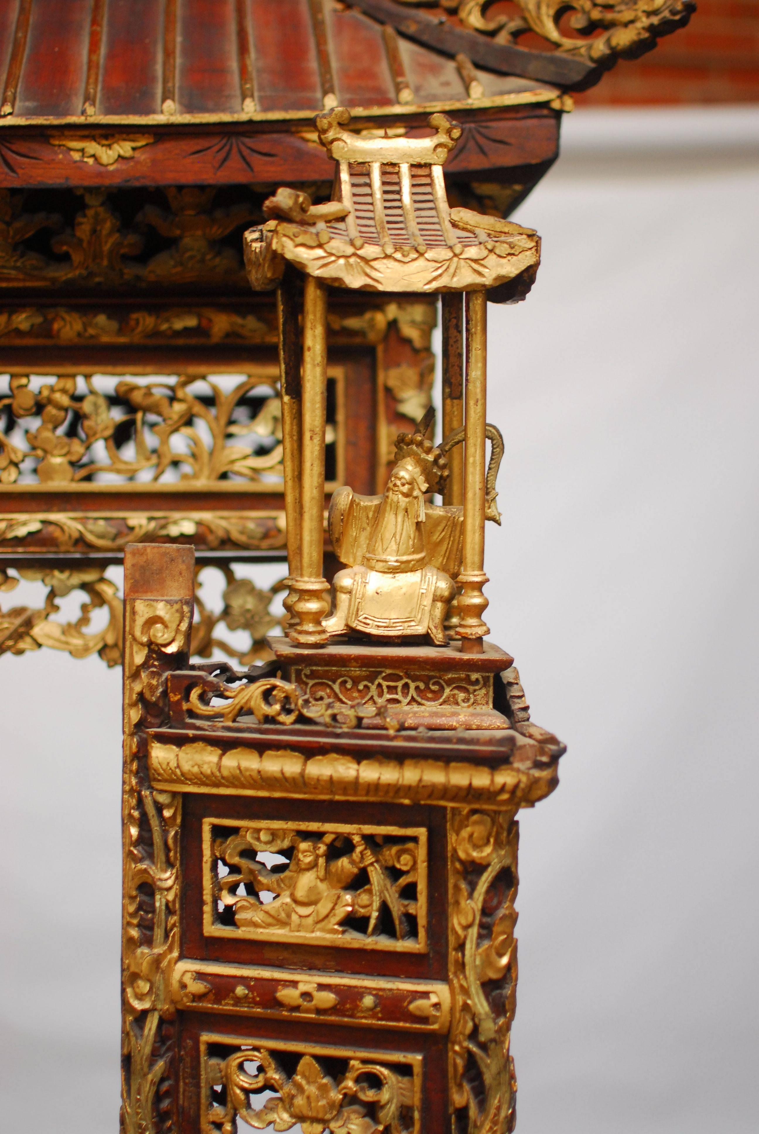 Monumental Chinese carved temple shaped altar piece featuring a pagoda top and finished in red lacquer and gilt. Stands nearly 7' feet tall. Exquisitely carved ancestral shrine or Buddhist altar for Butsudan. Two smaller pagodas on carved gilt bell