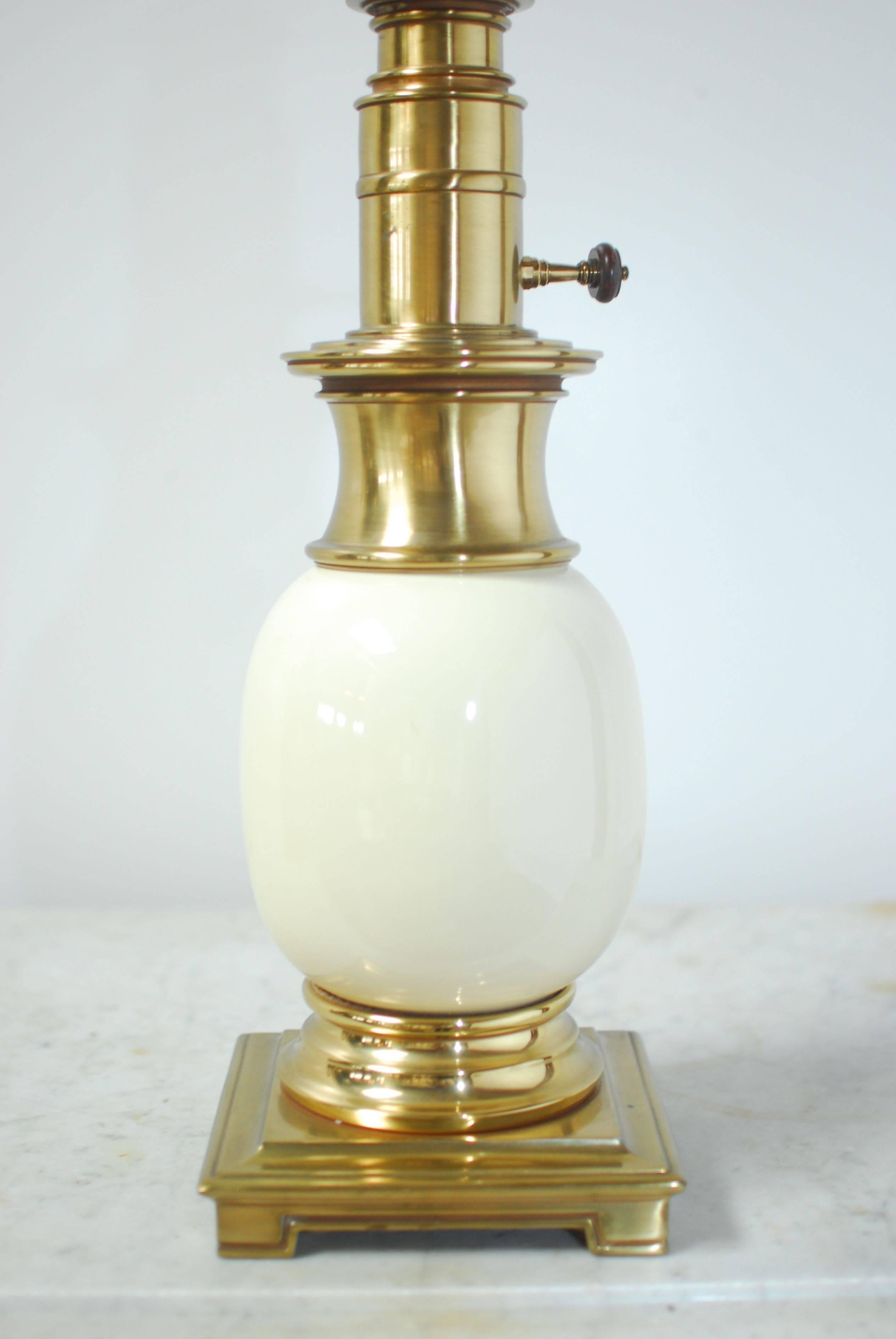 Hollywood Regency brass table lamp by Stiffel featuring a cream colored porcelain 