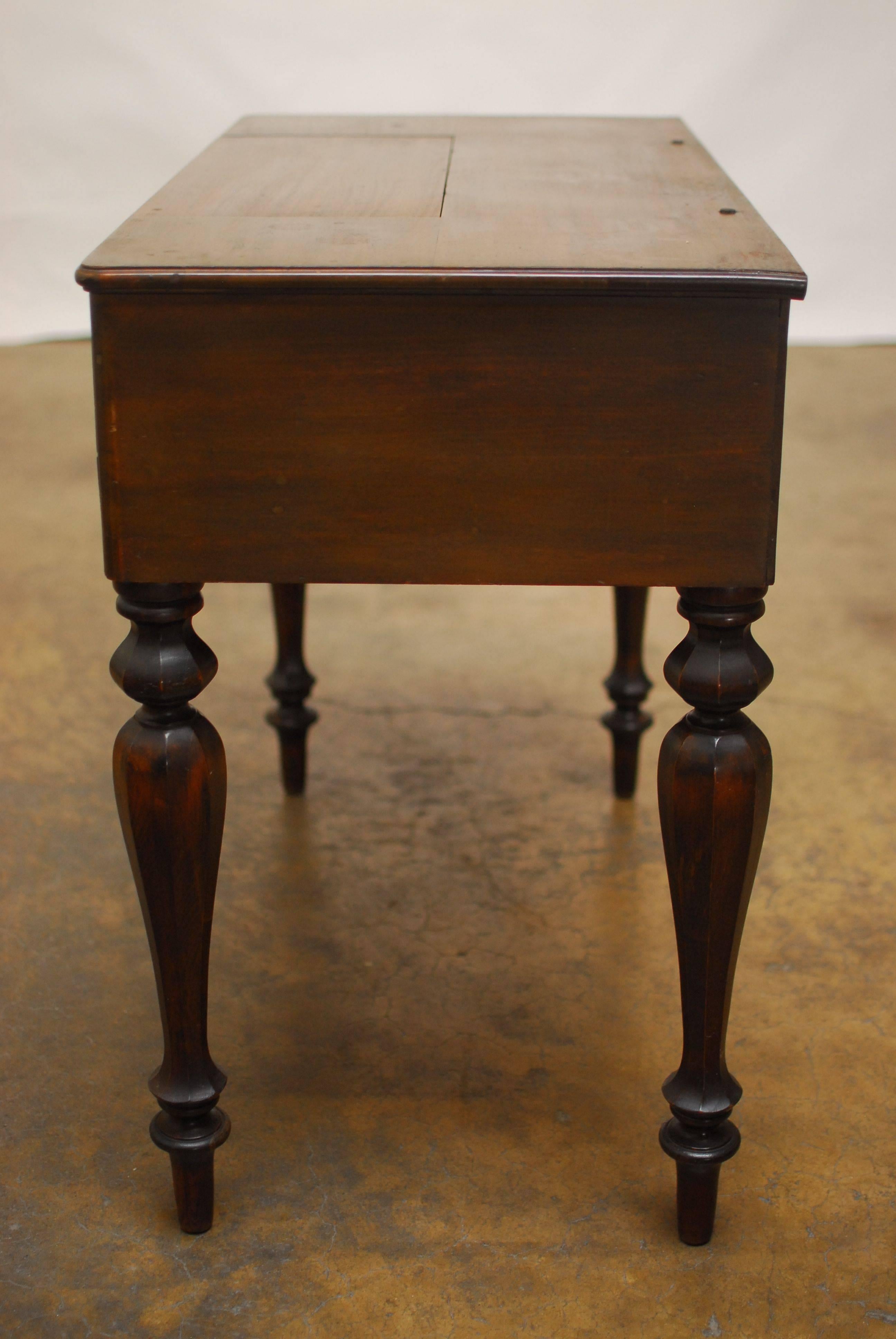 Mahogany writing table or secretary with a flip-top hinged single drawer that reveals a pullout desktop with multiple storage bins. Known as a spinet or piano desk because when closed it resembles a musical instrument of the harpsichord family.