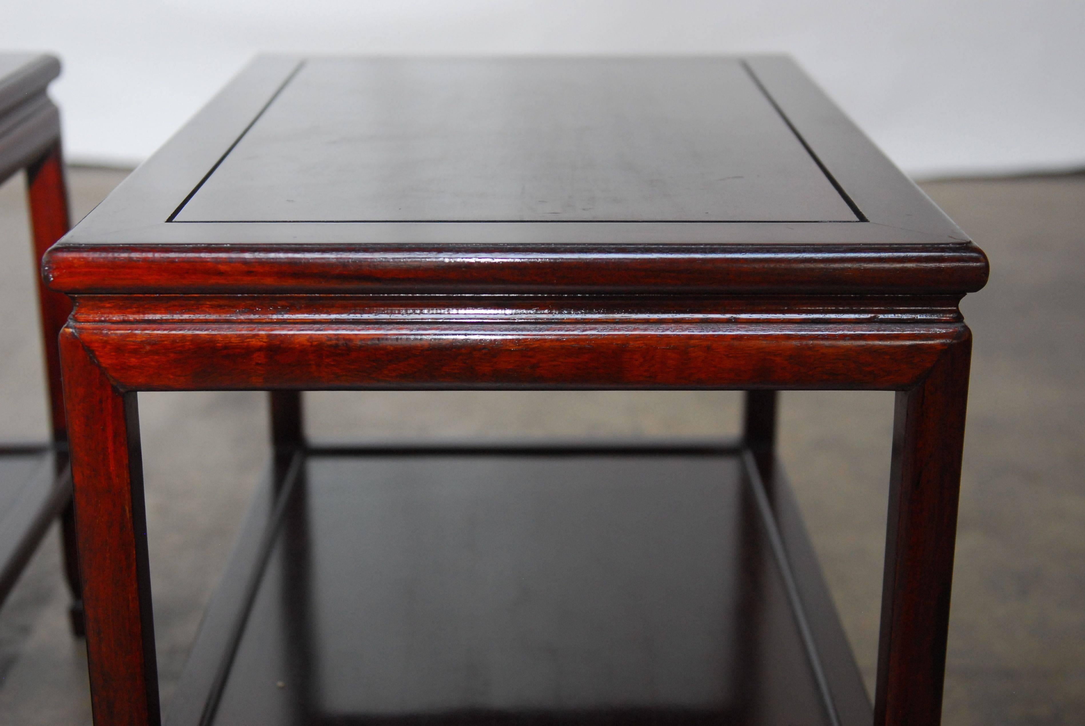 Pair of carved Rosewood side tables made in the Ming style featuring a floating top panel and chow feet. Stretchered legs supporting a shelf with old world joinery. These end tables feature a deep, rich Rosewood finish.