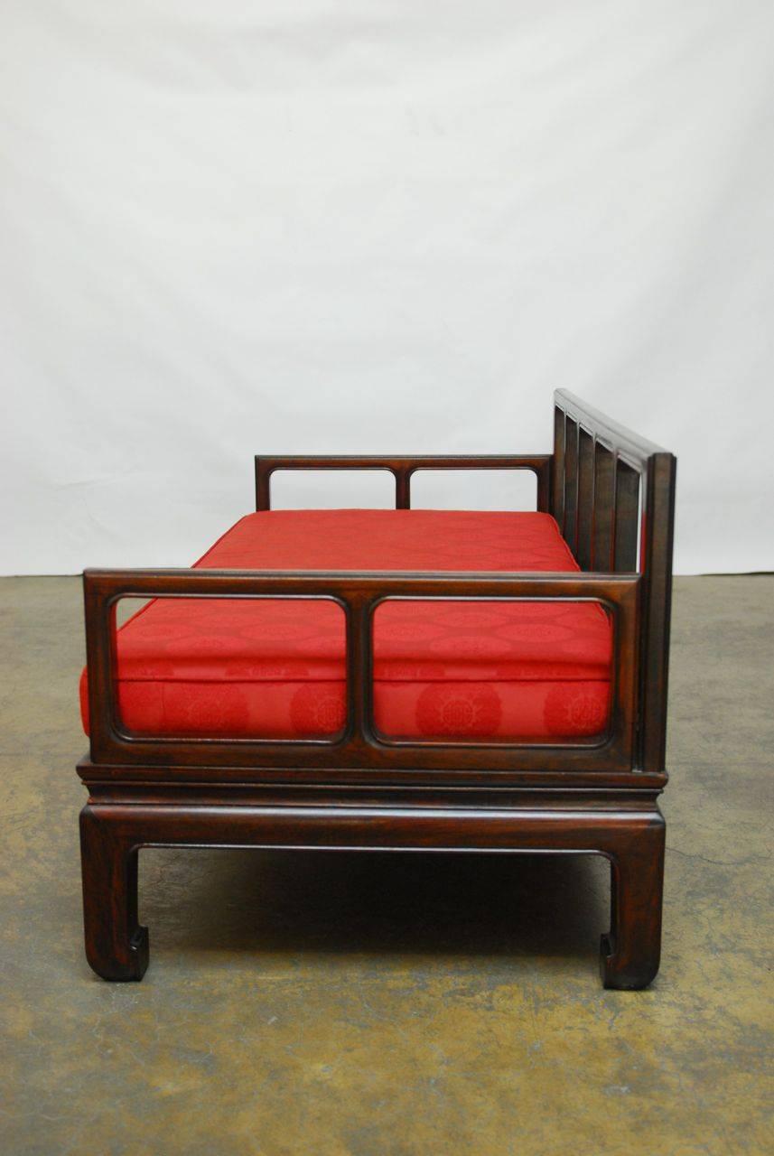 Exquisite Chinese carved rosewood daybed sofa made in the Classic Ming style. Featuring a geometric open carved frame with a floating top panel and chow legs. Finished in a deep mahogany with all the original seat pads. Measurements were taken