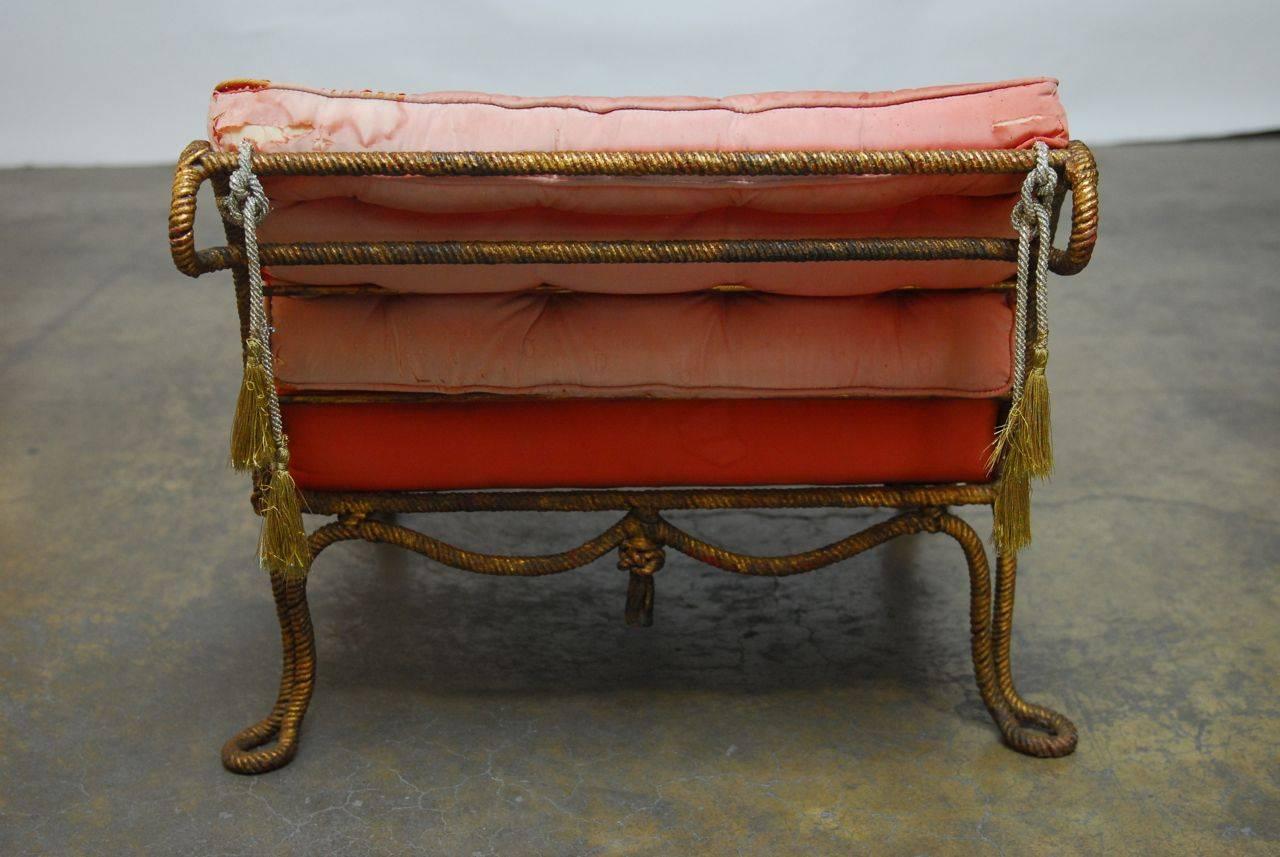 Fabulous French gilt-metal rope slipper chair made in the manner of A.M.E. Fournier. Featuring gilt rope legs and feet with rope swag sides and knot tassels. The back has a scrolled rest and there are two padded tufted cushions finished in red silk