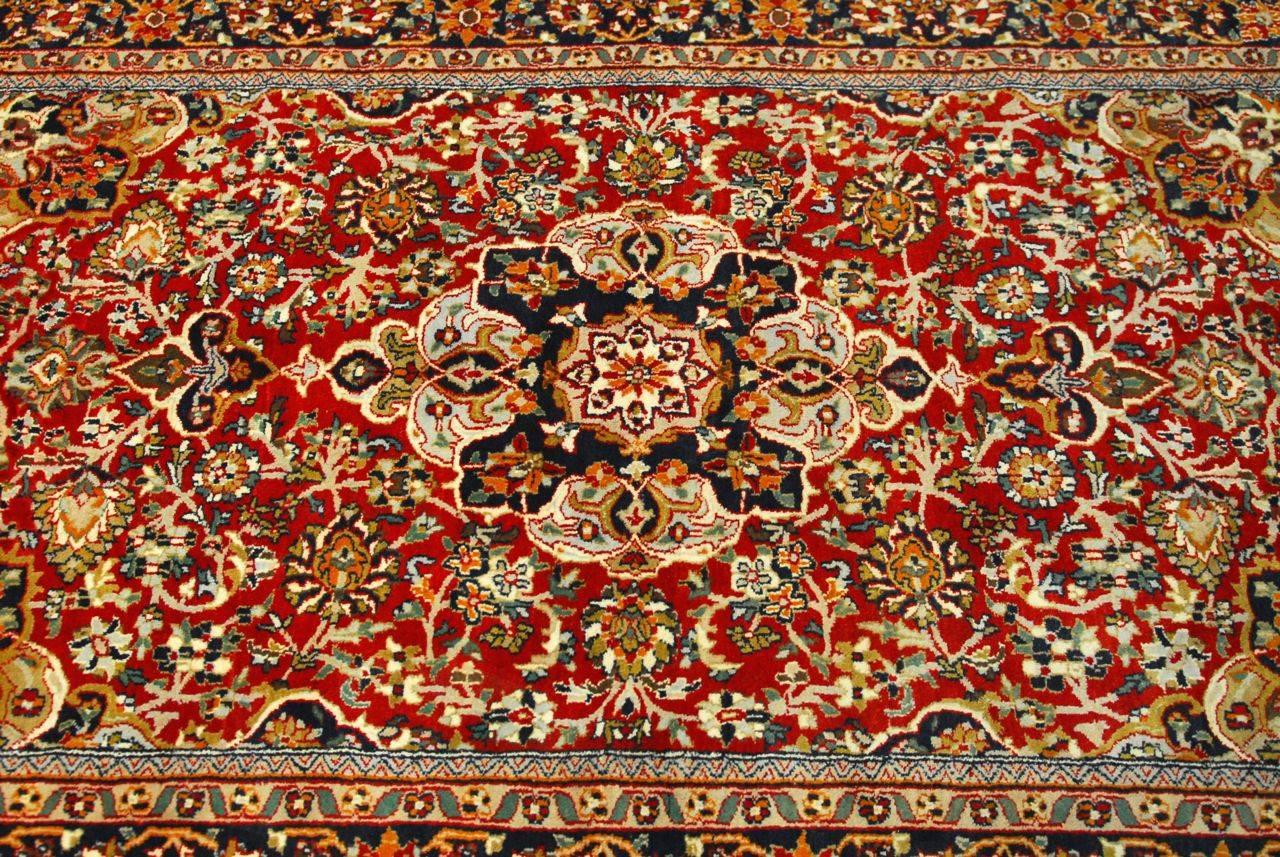 Classic Persian Isfahan rug featuring a center medallion and intricate patterns of palmettes and arabesque designs. Produced with high density knots of hand-knotted wool. Vibrant colors throughout the field and borders.
