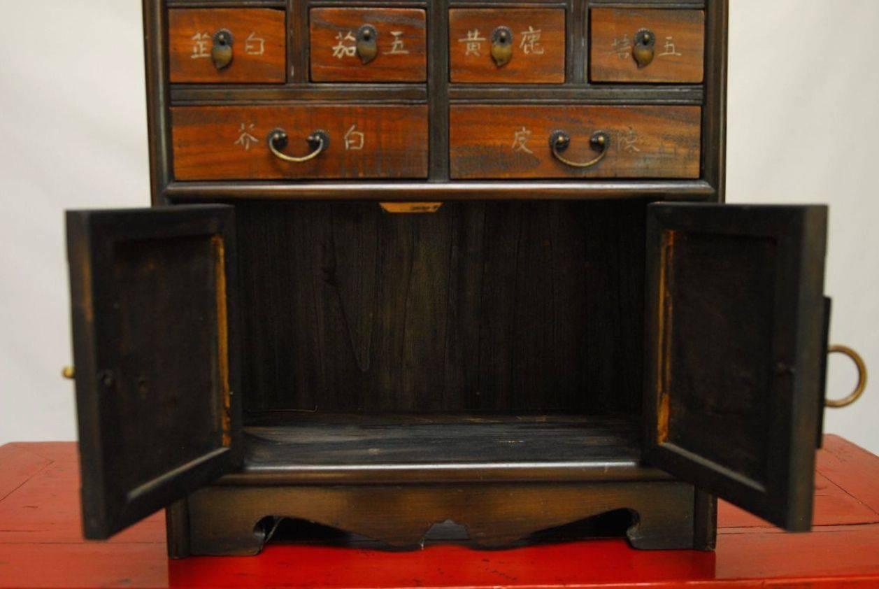 Exceptional and detailed Chinese counter-top medicine cabinet from a Chinese apothecary shop in Korea. Korean influences may be seen in the heavy and elaborate brass strap hinges. Chinese characters label each drawer with a brass pull in the center.