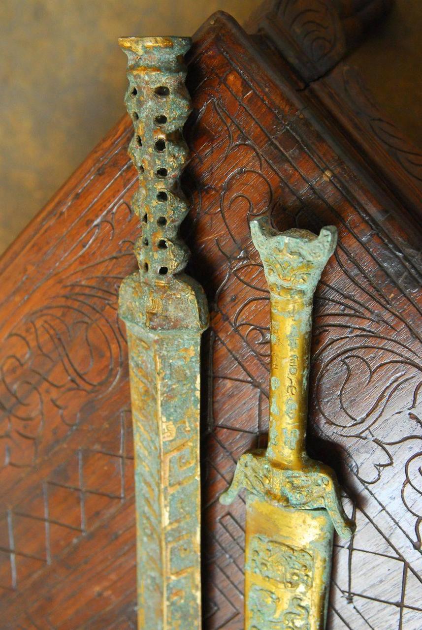 Large archaic patinated swords inscribed with ancient classical Chinese characters dating to the unification of china under the Qin emperor. One includes an elaborately decorated and patinated brass sheath. Each weighs approximately 4 pounds. The