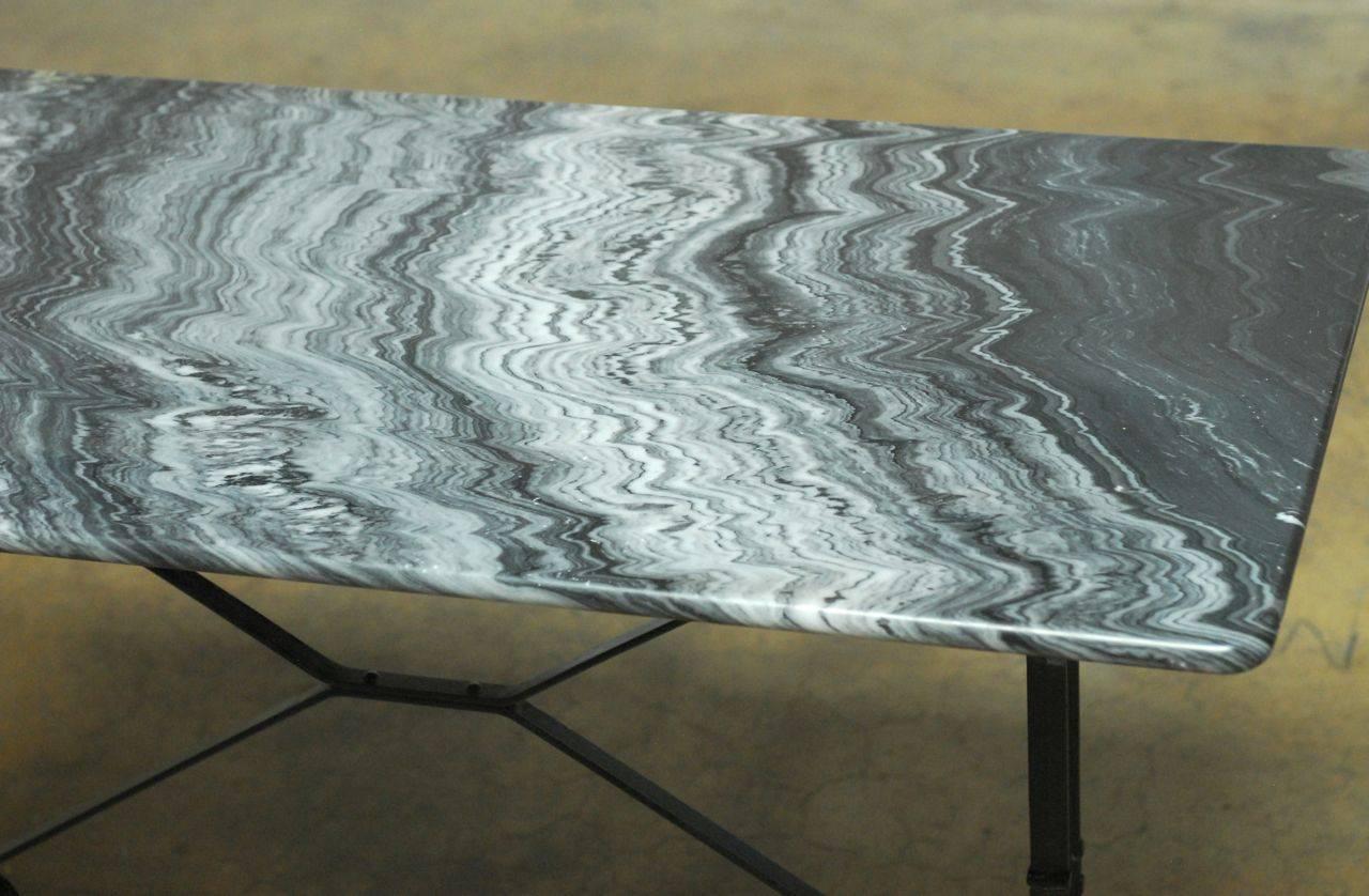 Impressive French bistro table featuring a dark grey slab of marble with an intricate vein pattern. Supported by a cast iron base with cross stretchers in a sleek black finish.