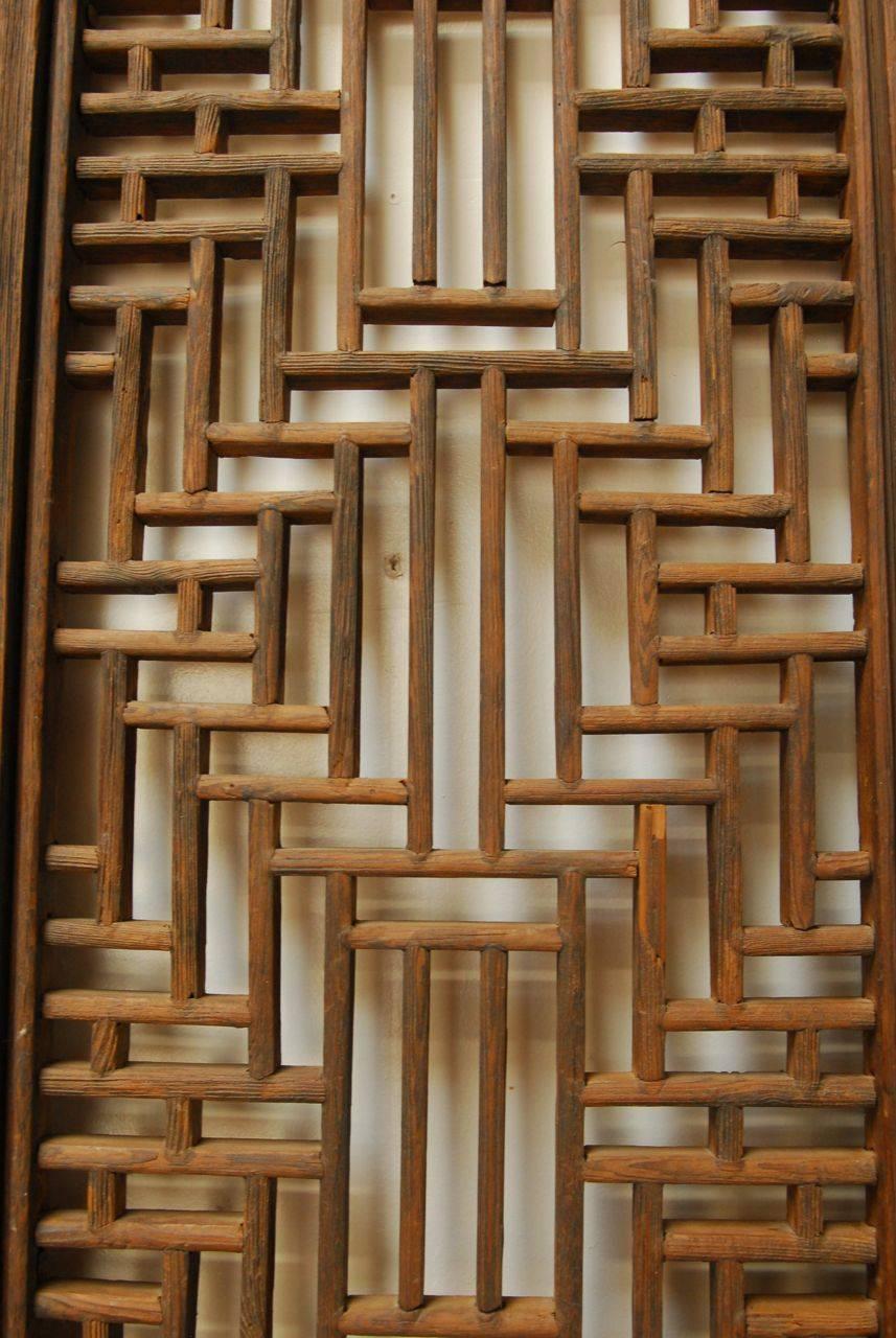 Exquisite hand-carved Chinese door panels featuring intricate geometric lattice work. Constructed using mortise and tenon joinery, with original iron hardware and pulls. Installation of hinges would make an impressive screen. These open fretwork