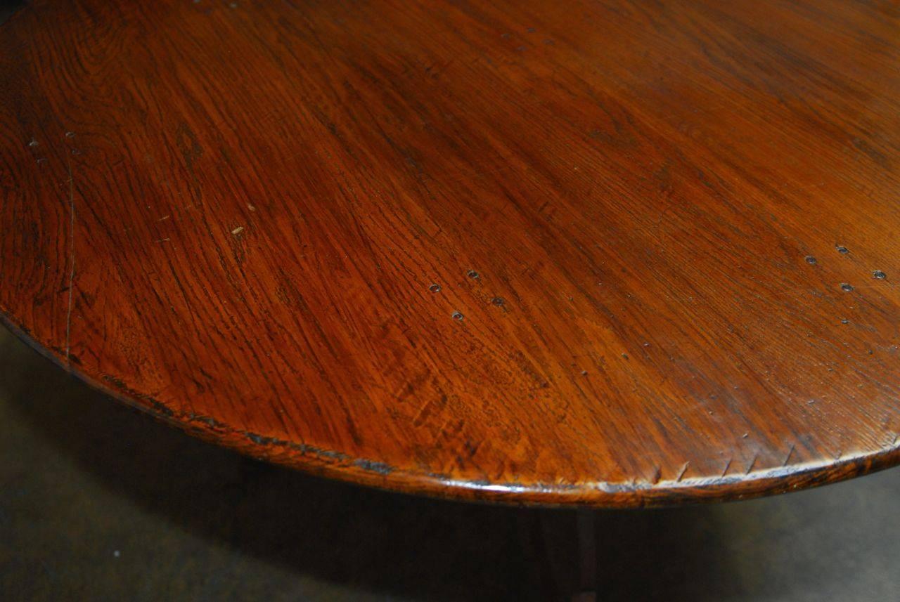 Impressive Italian round dining table made of reclaimed oak and supported by a wrought iron base featuring decorative scrolled legs and feet. Solid oak top with lovely distressed wood look and a heavy iron base with a patinated iron finish.