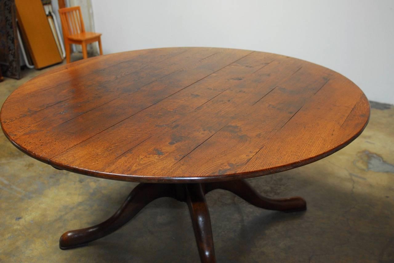Rustic Italian round carved solid walnut pedestal dining table made in the Georgian taste. Featuring a large turned pedestal column supported by massive legs. Beautifully constructed with a distressed country finish and a top that expands to