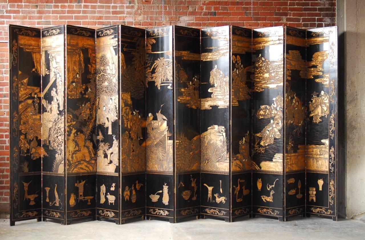 Monumental Chinese 12-panel folding coromandel screen with double sided decoration. Featuring thick layers of lacquer incised with gold leaf depicting mandarins in a floral garden. The reverse side having celestial figures painted in an array of