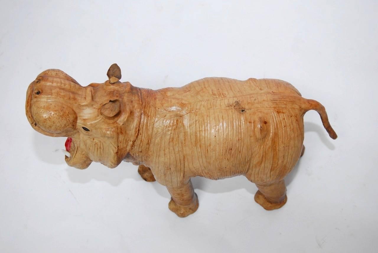 Charming leather covered hippo depicted yawning. Made in the style of Abercrombie and Fitch animal leather footstools from the early 20th century. Features beaded eyes with a wide open mouth and red tongue. The vintage leather has a detailed and