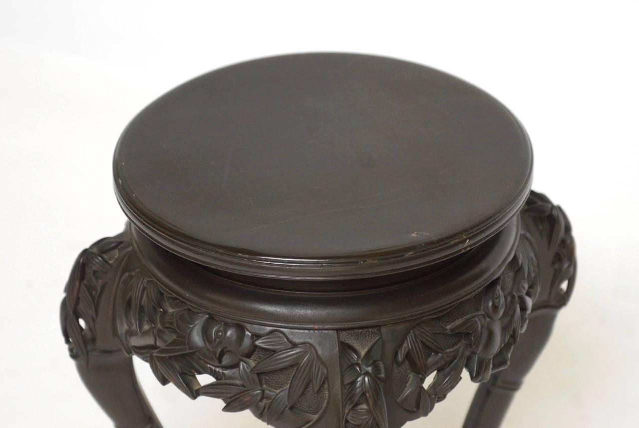 Carved Japanese stand that could be used a stool or a drink table featuring faux bamboo legs with an intricately carved apron of bamboo leaves and birds.
Round floating top or seat with a dark ebonized style finish.

 