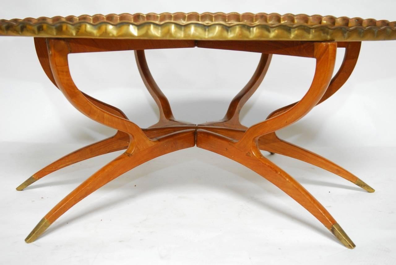 Large Mid-Century folding brass tray table with an oval top featuring a spider six-leg base made of mahogany. Each leg has a brass protected foot and opens to a star-shaped base. The mahogany is beautifully grained and supports the large tray with a