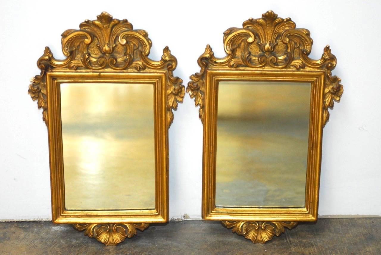 Opulent pair of Italian giltwood and gesso mirrors made in the Rococo taste. Each having a scroll and acanthus decorated frame centering a rectangular looking glass. In excellent condition given age and use.