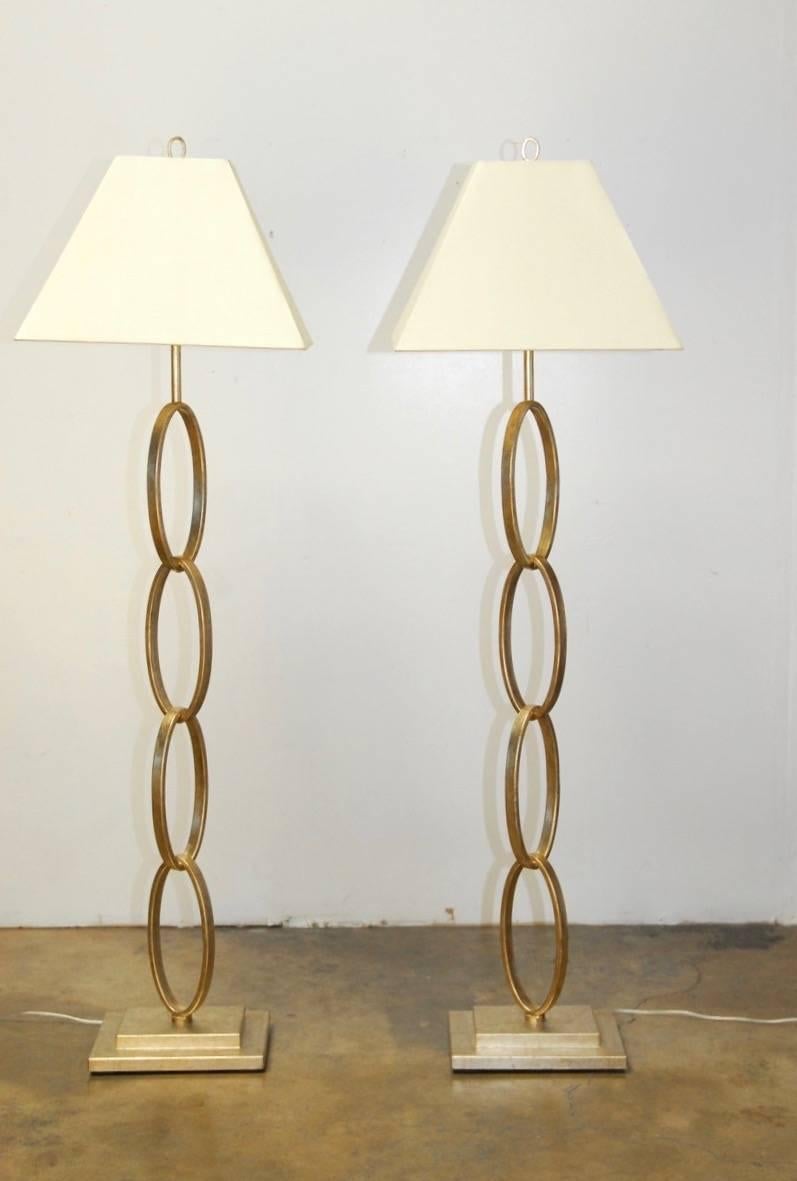 Shimmery pair of silver leaf bangle chain link floor lamps by Currey and Company. Crafted from wrought iron rings forming a modern chain and covered with hand-applied silver leaf. Includes two champagne white silk shades. The chain links are