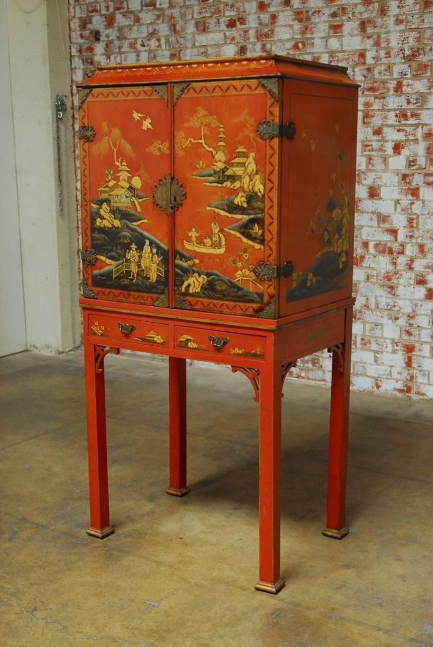 Charming Chinese Chippendale style red lacquer cabinet or liquor cabinet on stand. Featuring a Japanned case with gilt idyllic scenes of rivers, trees and pagodas. The case is fronted by two large doors that open to two storage shelves and topped