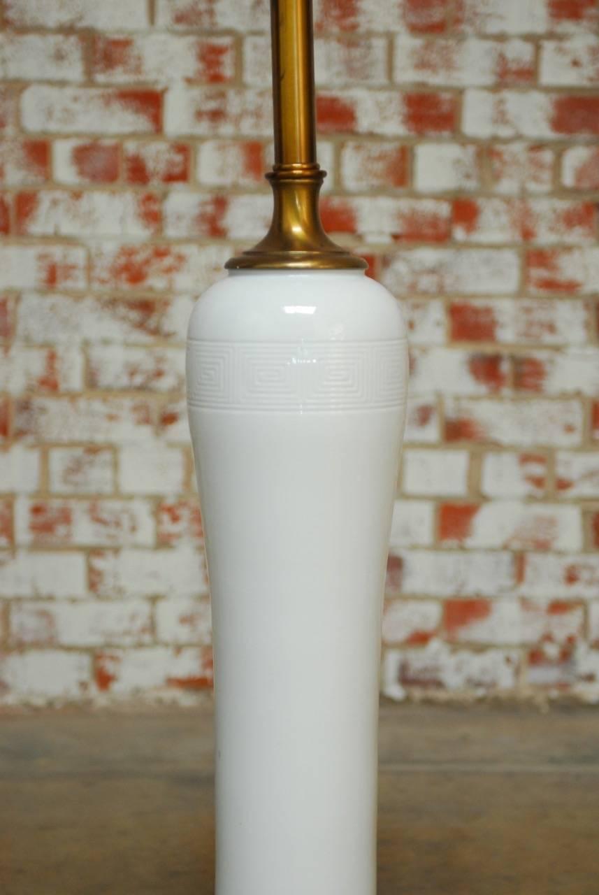 Monumental Chinese porcelain Blanc de Chine vase table lamp featuring a long, elegant, tapered vase mounted on a gilded metal pedestal and topped with a brass lid and hardware. Large enough to be used as a floor lamp with a custom shade or a table