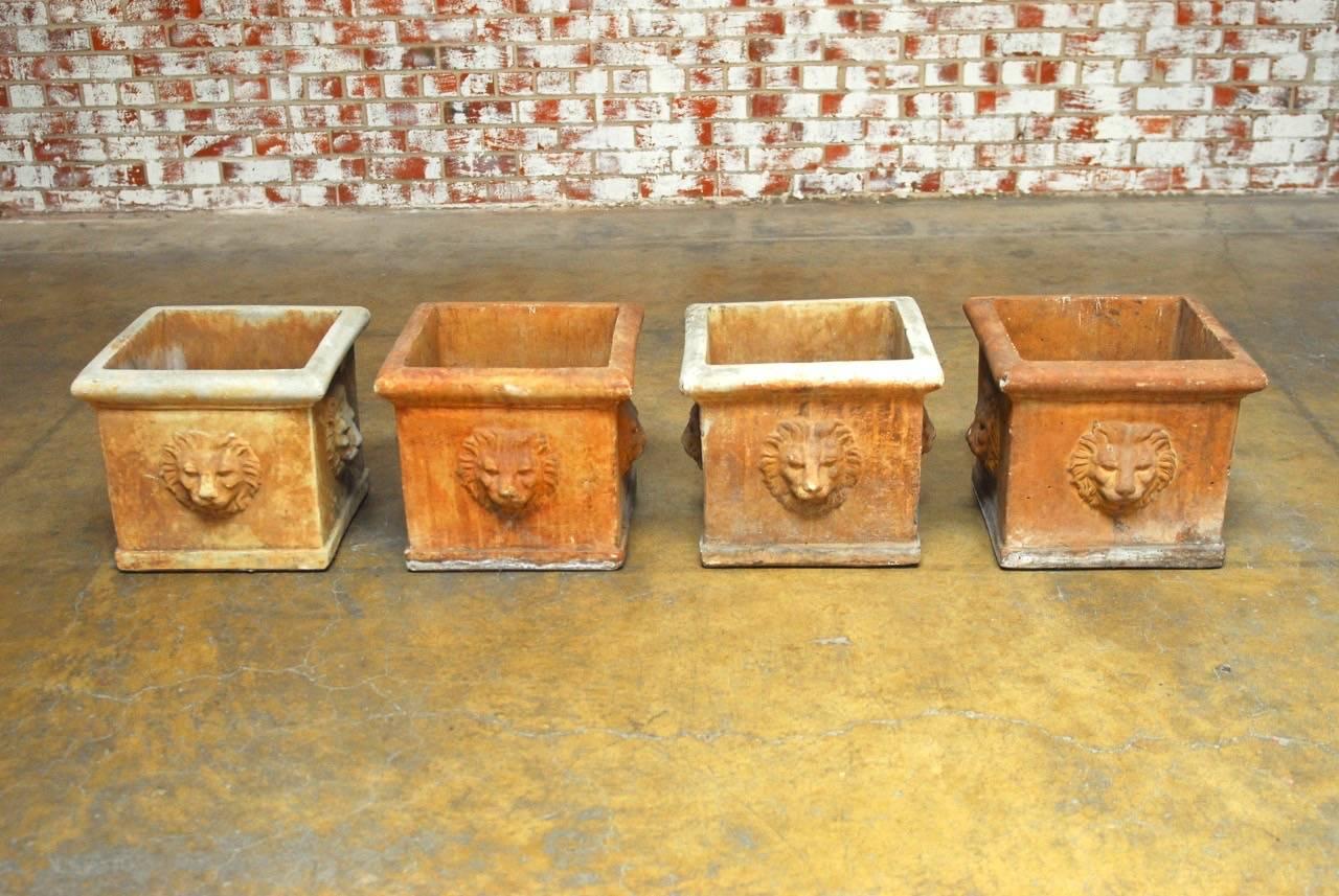 Set of four European or continental style planters made of sandstone featuring a lions head decoration on each side. Produced by famous San Francisco, CA garden statuary company 