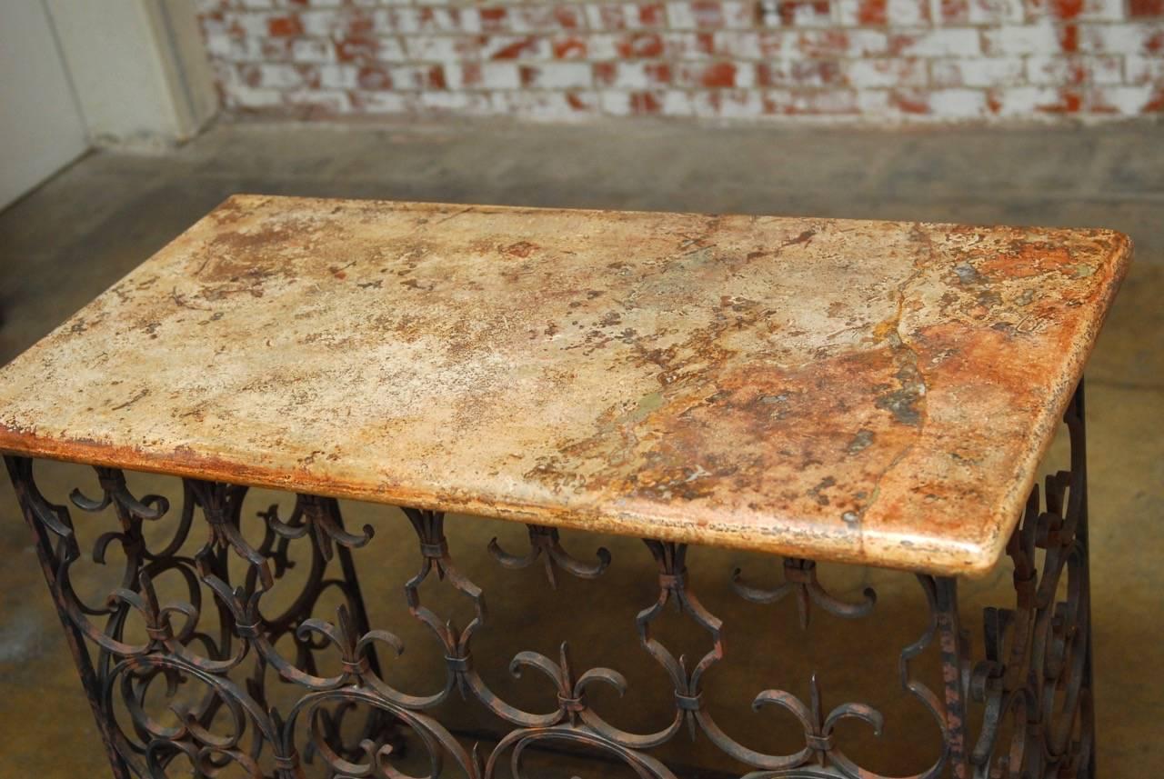 Spanish style wrought iron and marble top console table featuring a pierced quatrefoil design base. Topped with a fitted slab of Italian marble having a thick bull-nose edge. The table is decorated on three sides and supported by five shaped feet.