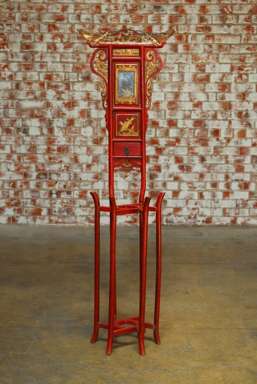 Ornate Chinese red lacquer and parcel-gilt washstand with small storage drawer and mirror. Features a carved crest decorated with opposing Phoenix birds above a scrolled frame. Supported by six long elegant legs with decorative stretchers. Made to