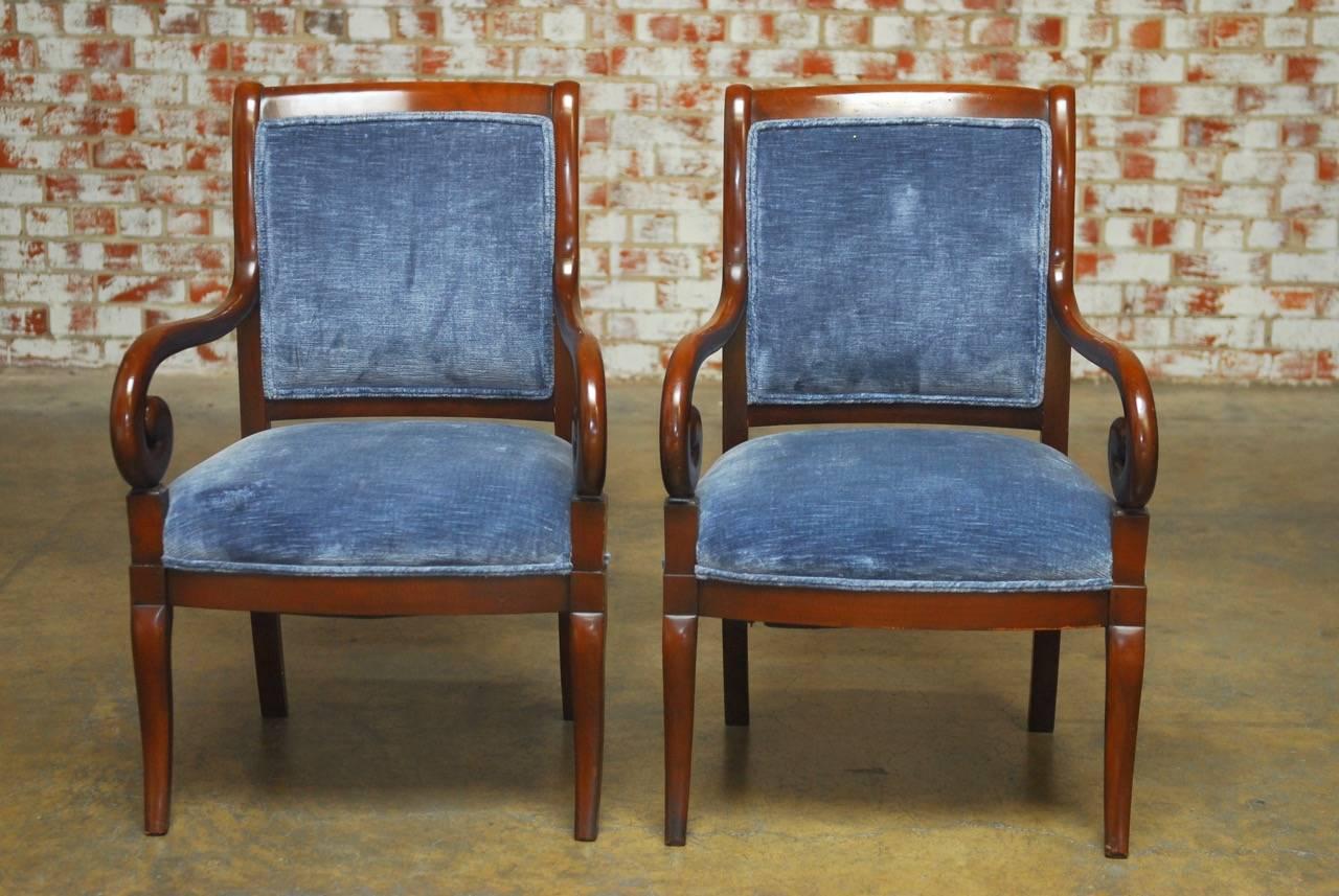 Fine pair of English mahogany library armchairs. Made in the Regency taste featuring large scrolled arms and a generous seat. The upholstered velvet chairs have a square back with a scrolled crest and are supported by cabriole legs in the front.