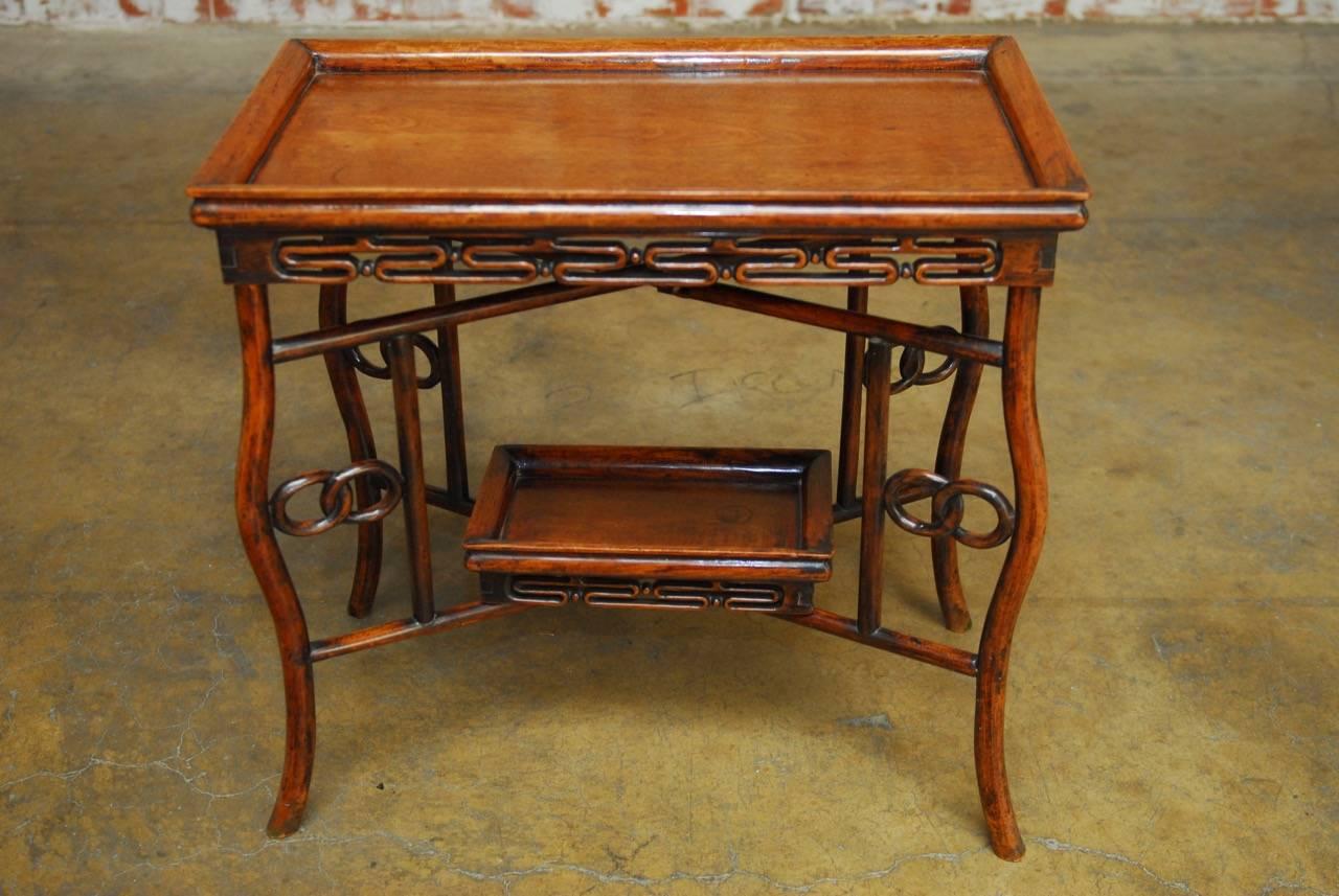 Elegant Chinese Qing carved rosewood folding tray table featuring a lower removable tray. Rectangular tray top with a raised moulded gallery above a large floating panel of rosewood decorated with a geometric design frieze. Supported by a folding