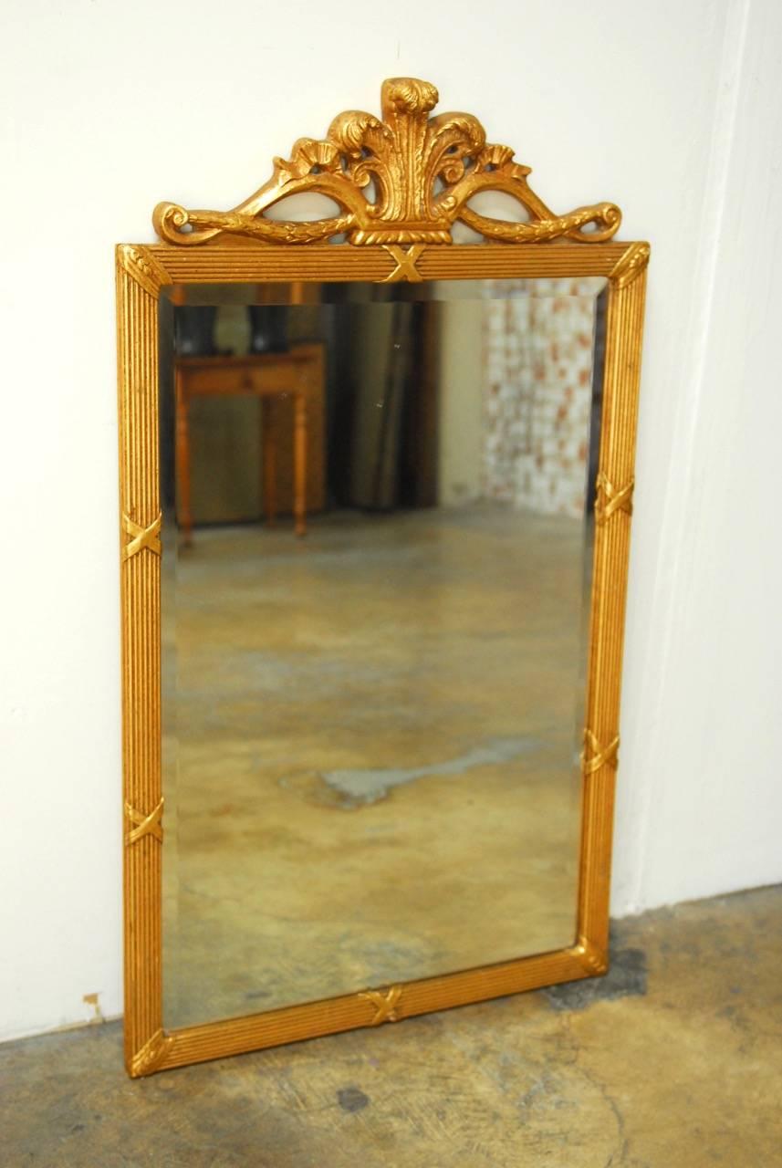 Impressive Louis XVI giltwood bevelled mirror featuring a reeded frame decorated with cross ribbons. Surmounted by a fleur de lys motif carved crest. Beautifully gold leafed by hand. Provenance: from the St. Francis Hotel San Francisco, CA.