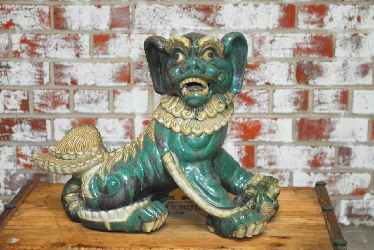 Fantastic pair of Chinese glazed turquoise porcelain foo dogs or foo lions. Male and female with the male being slightly larger. Expressive faces with a rich vintage patina on the green turquoise and white glazed finish. Guardian temple dogs are