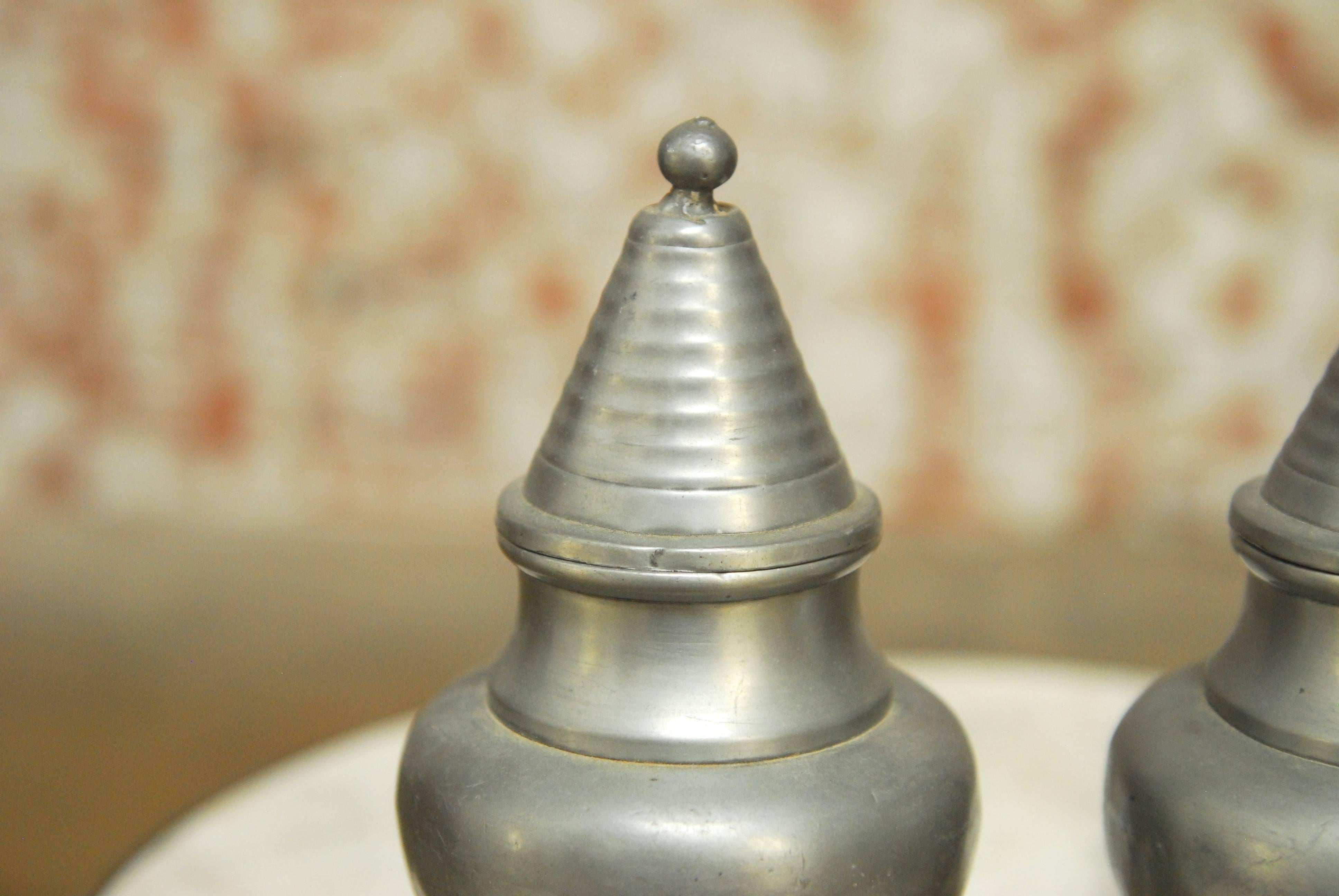 Charming pair of diminutive Chinese pewter lidded urns or vases featuring a turned finish with bell finials. Great for decoration, storage, or both. Minor dents consistent with age and use.
 