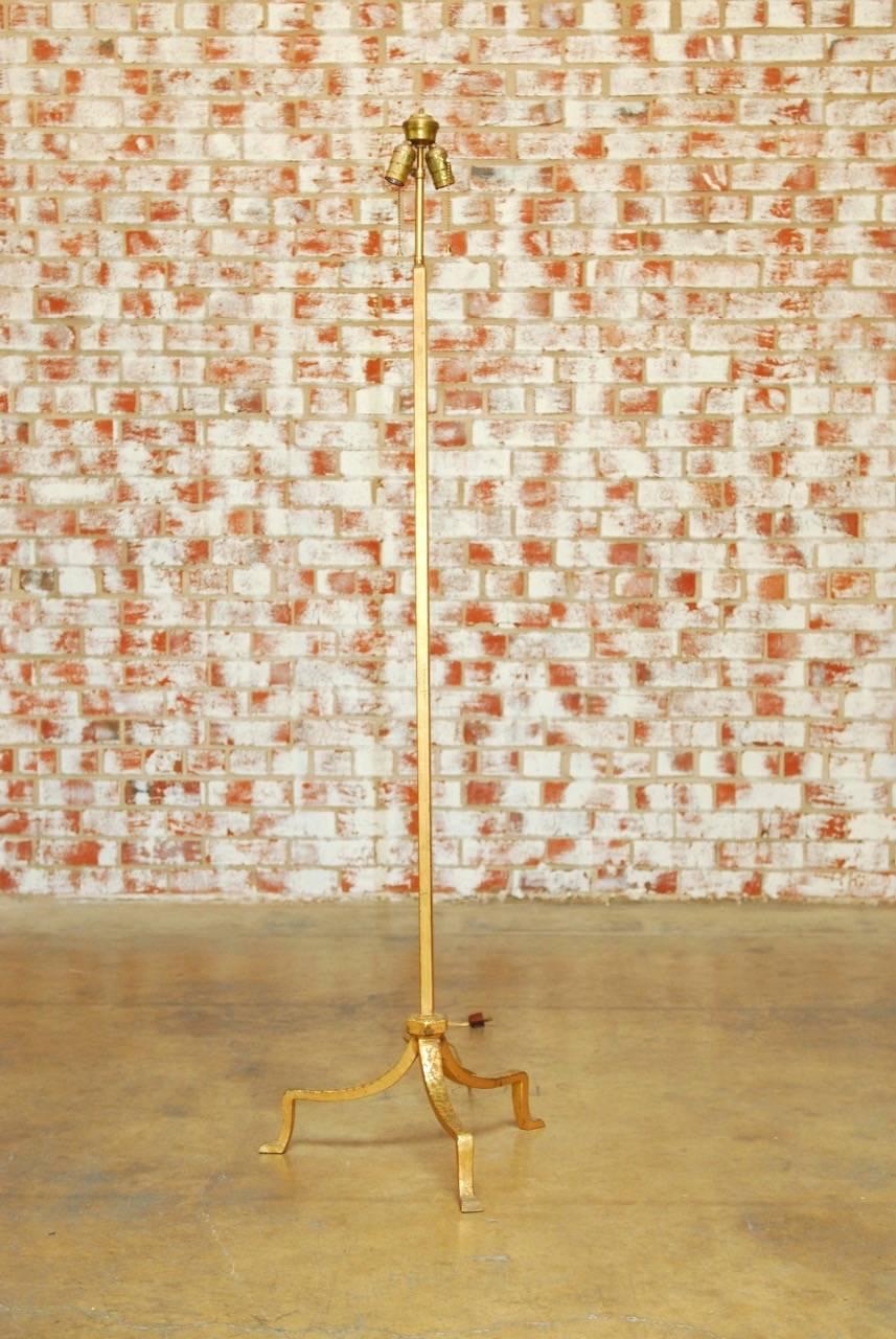 Elegant Hollywood Regency Italian wrought iron floor lamp featuring a handcrafted gilt finish. Supported by a footed tripod base and topped with an height adjustable duel light head. Does not include shade or finial.