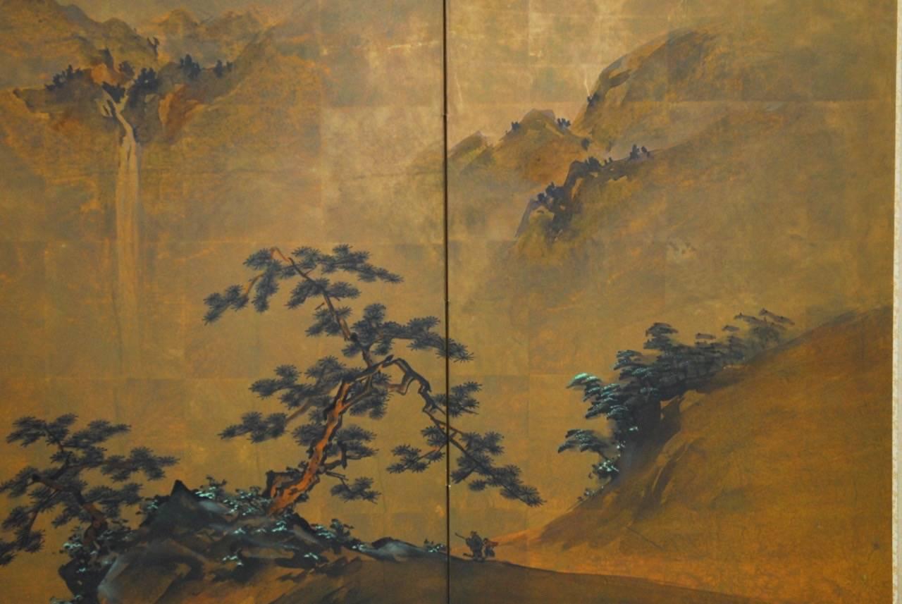 Idyllic Japanese four-panel painted landscape byobu screen. Features a delicate painted scene of mountains and trees on a gilt background with beautiful shading and blue highlights. Signed with two seals on upper right. Set in an ebonized frame with