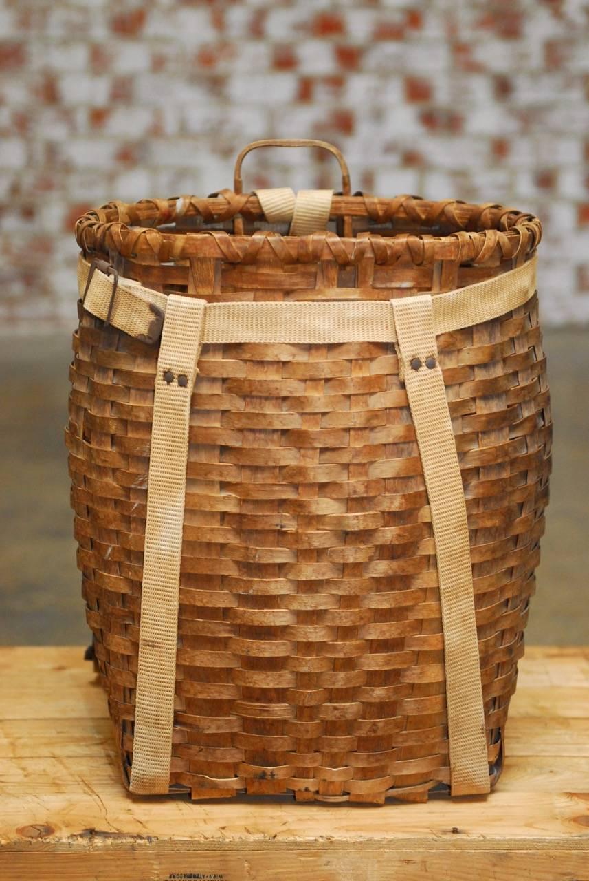 Large American adirondack trappers basket or pack basket made from flat woven ash. Features vintage canvas shoulder straps and bentwood construction frame with a handle on top. Attributed to L.L. Bean. Also known as allagash packs. Great decorator