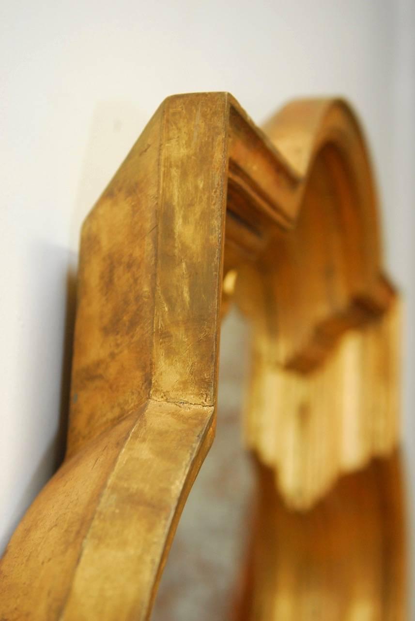 Fantastic Mid-Century Modern Italian handcrafted golf leaf quatrefoil mirror made in the Hollywood Regency period. Carved wood frame sections with a decorative stepped front and a rounded back and sides. Features a lovely distressed and patinated