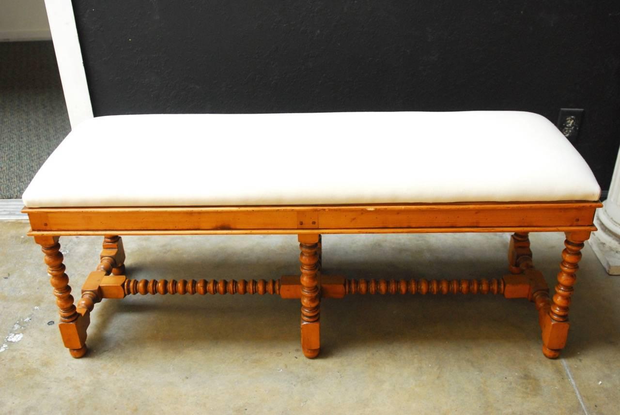 French country style pine turned leg bench featuring six turned legs conjoined with turned stretchers made of pine. Generous size upholstered in muslin fabric with a pad, ready for your custom upholstery. Tight wood peg joinery in an old world