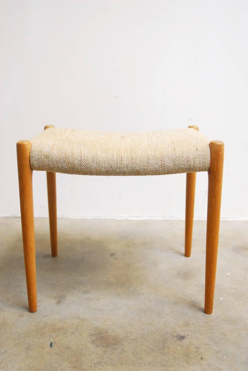 Midcentury Danish modern footstool upholstered in a vintage fabric. Supported by elegant tapered legs.