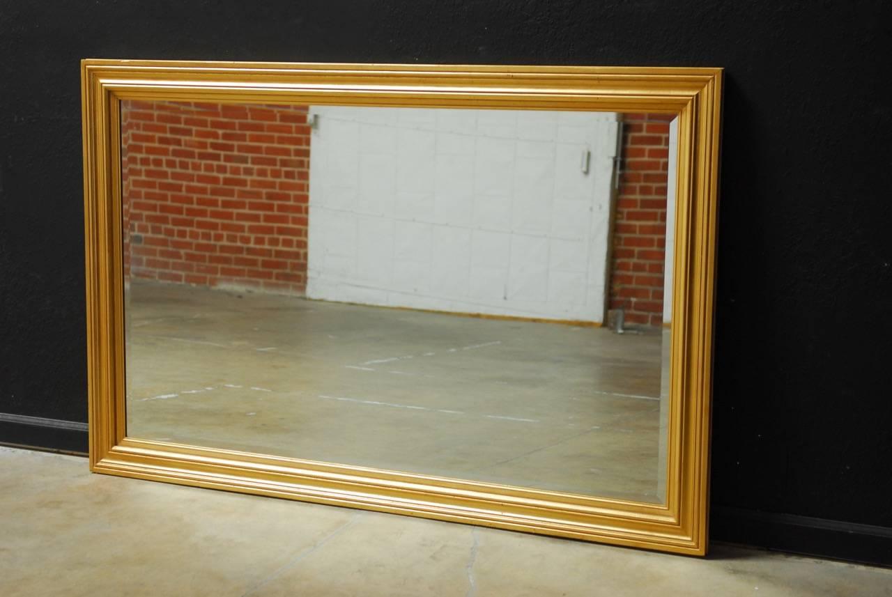 Stunning giltwood wall mirror featuring a hand-applied gold leaf finish. Produced by Windsor Art in California. The gilt frame showcases a thick, beveled glass that could be hung vertical or horizontal. The thick frame has a beautiful antiqued